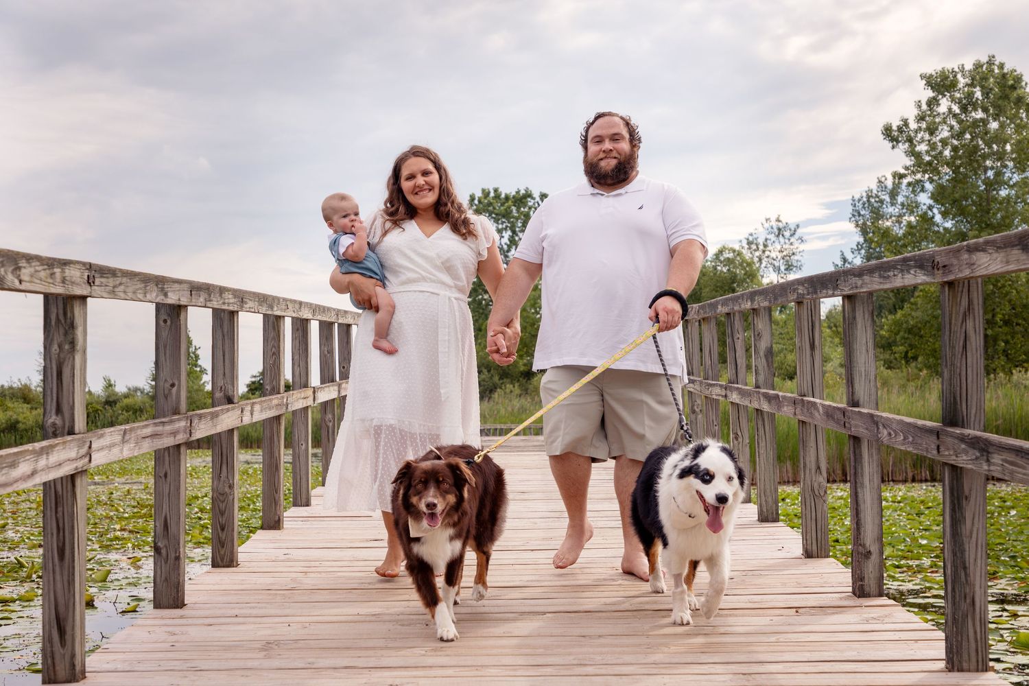 Family walking and playing on wooden boardwalk during summer photoshoot.