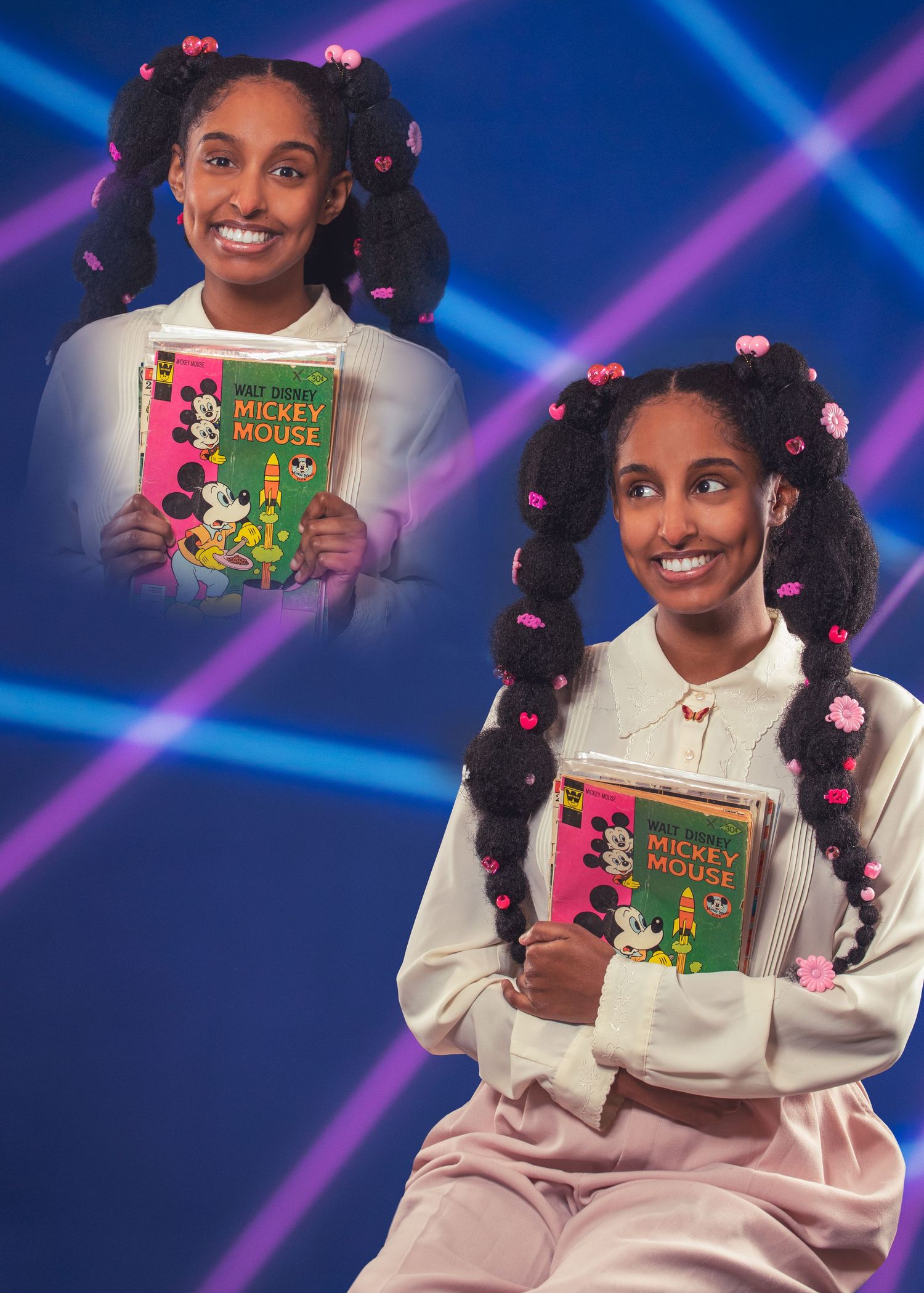 Child model in white outfit holding children's book with decorated hairstyle against blue stage lighting.