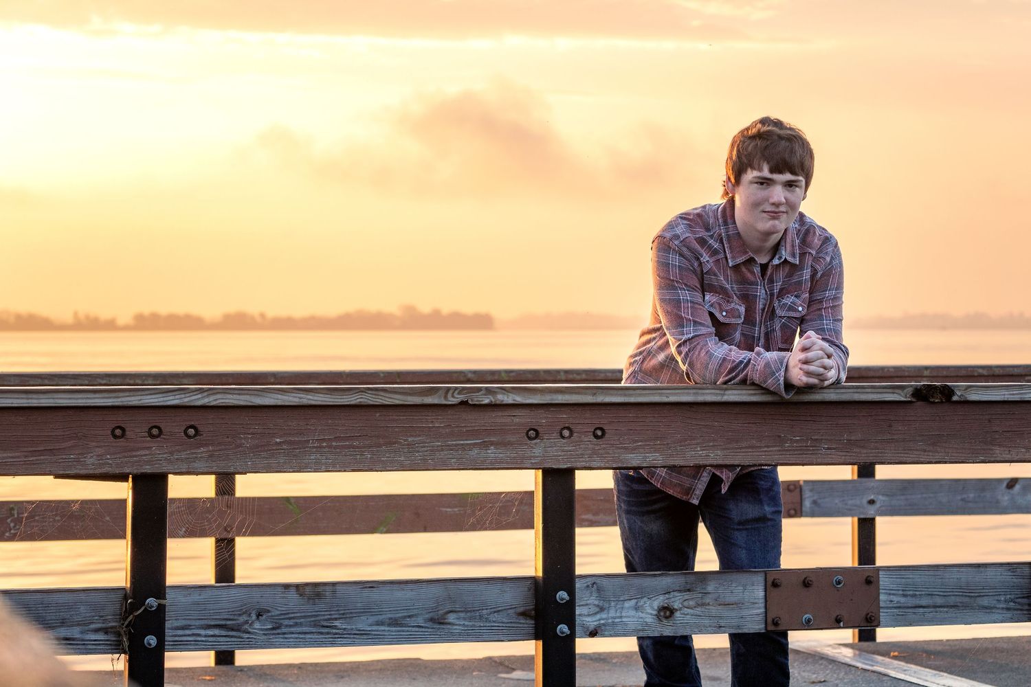 Wooden bench at sunset with warm orange sky creating a serene coastal atmosphere.