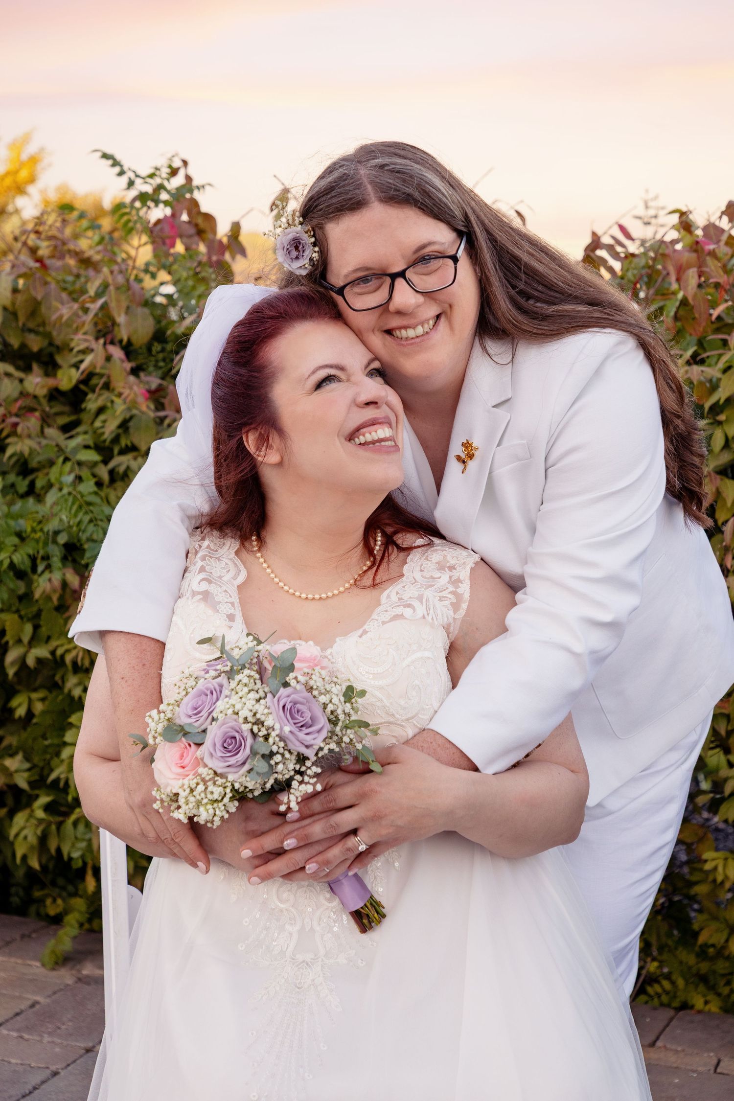 Joyful wedding couple sharing intimate moments while holding a pastel bouquet.
