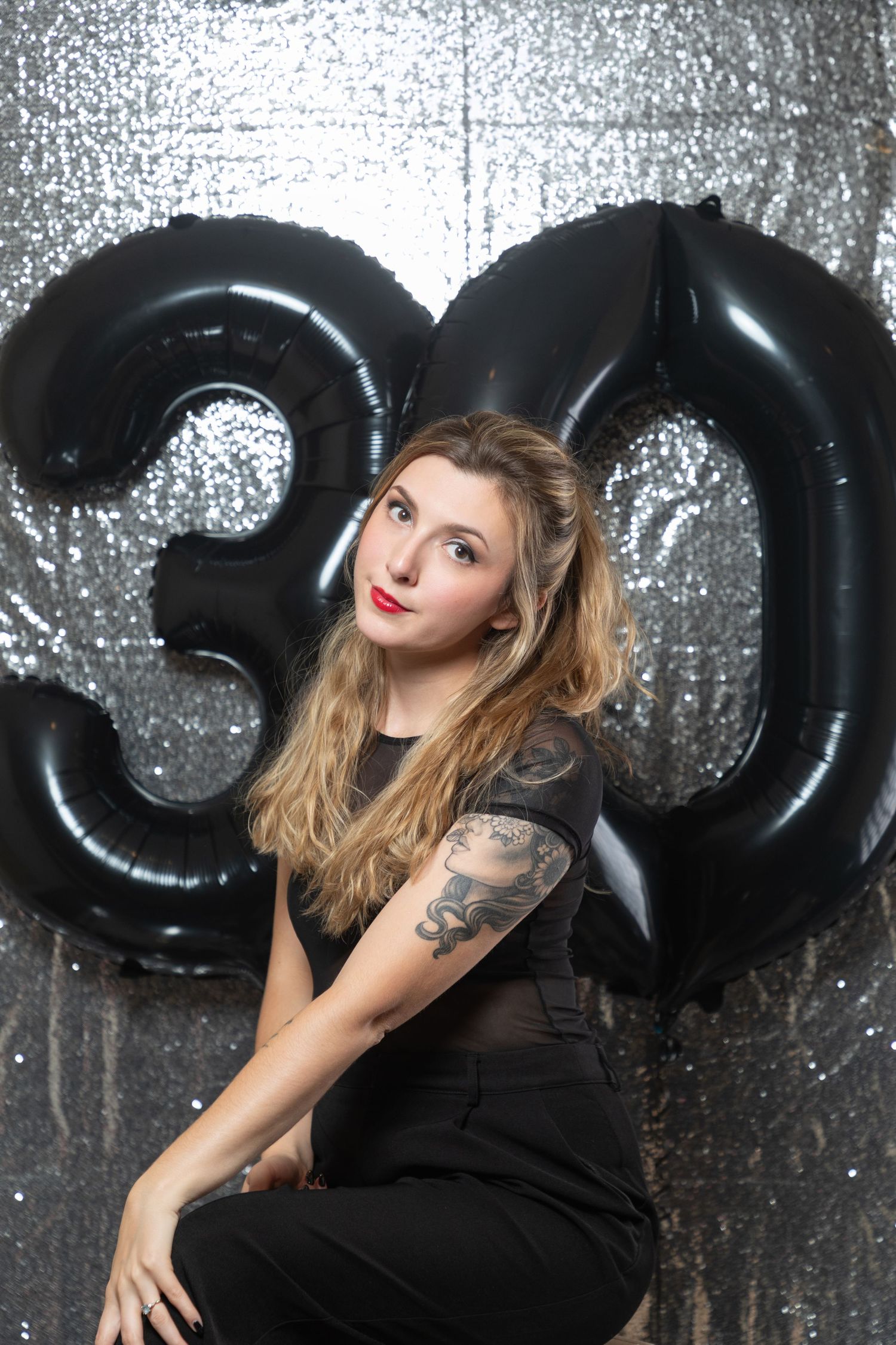 Glamour photoshoot with black balloon decorations and silver sparkly backdrop.