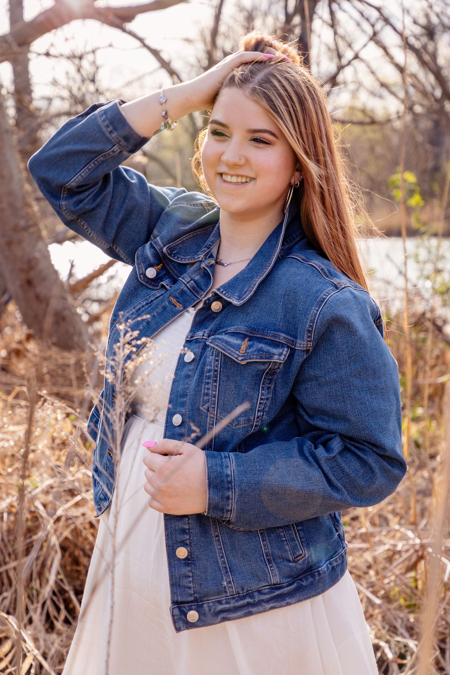 A casual outdoor portrait featuring a denim jacket and cream dress among autumn foliage.