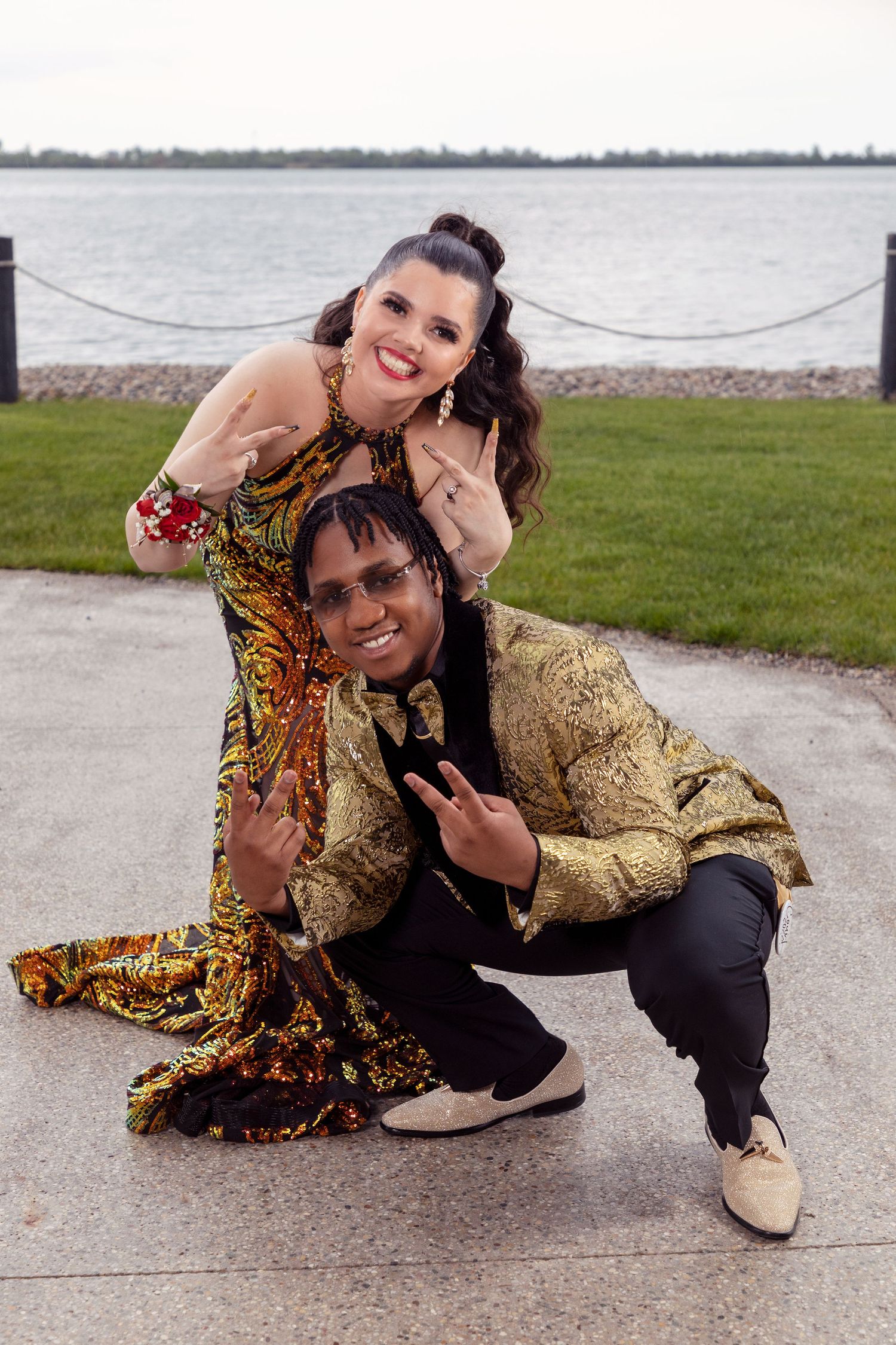 Friends in festive gold and patterned outfits posing playfully outdoors by the water.