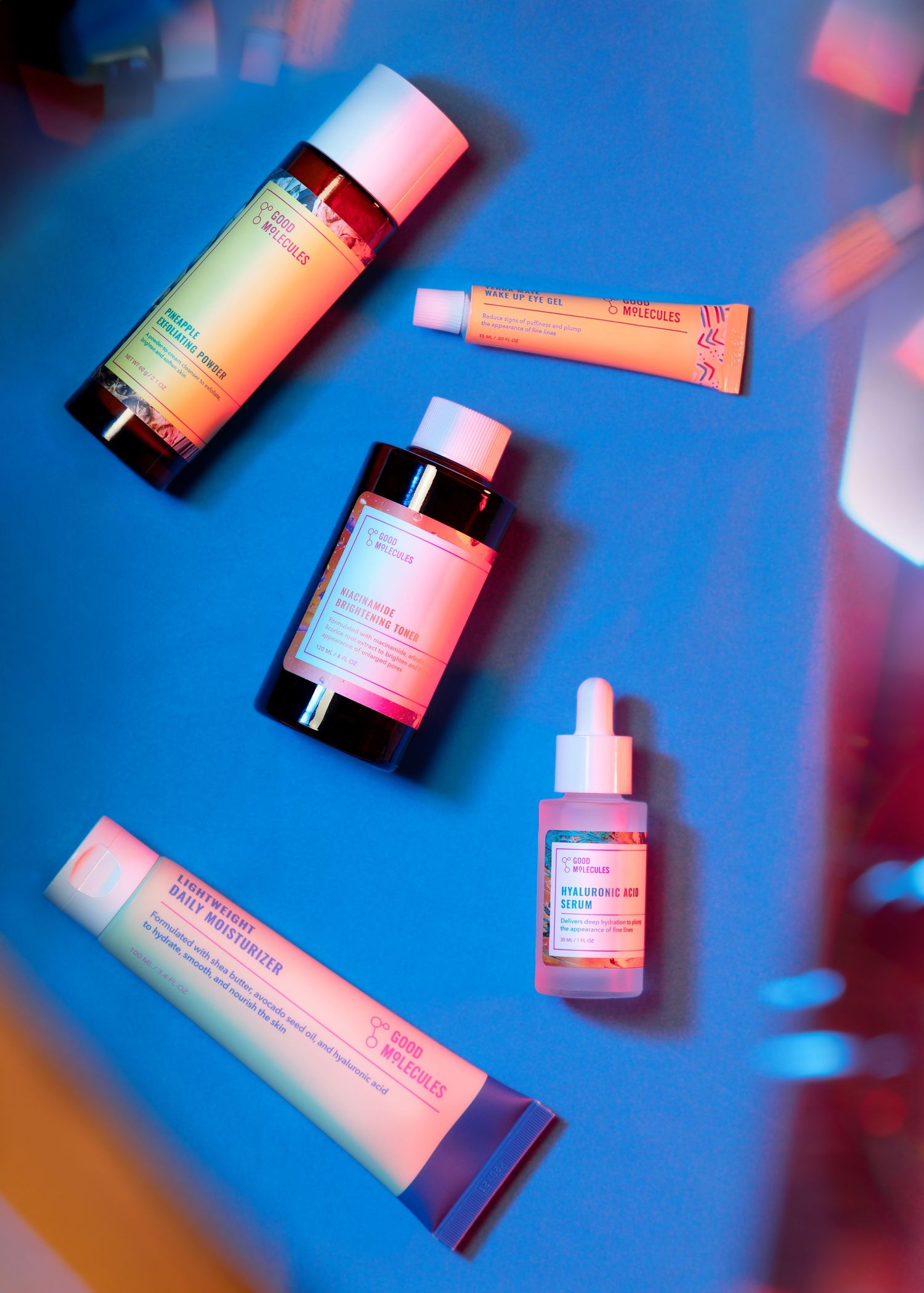 Beauty product bottles arranged on blue background with pink lighting effects.