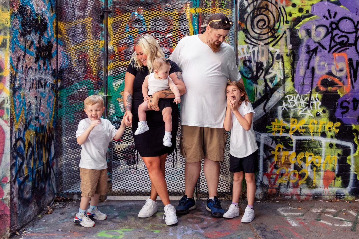 Family portrait session in front of vibrant street art and graffiti murals.