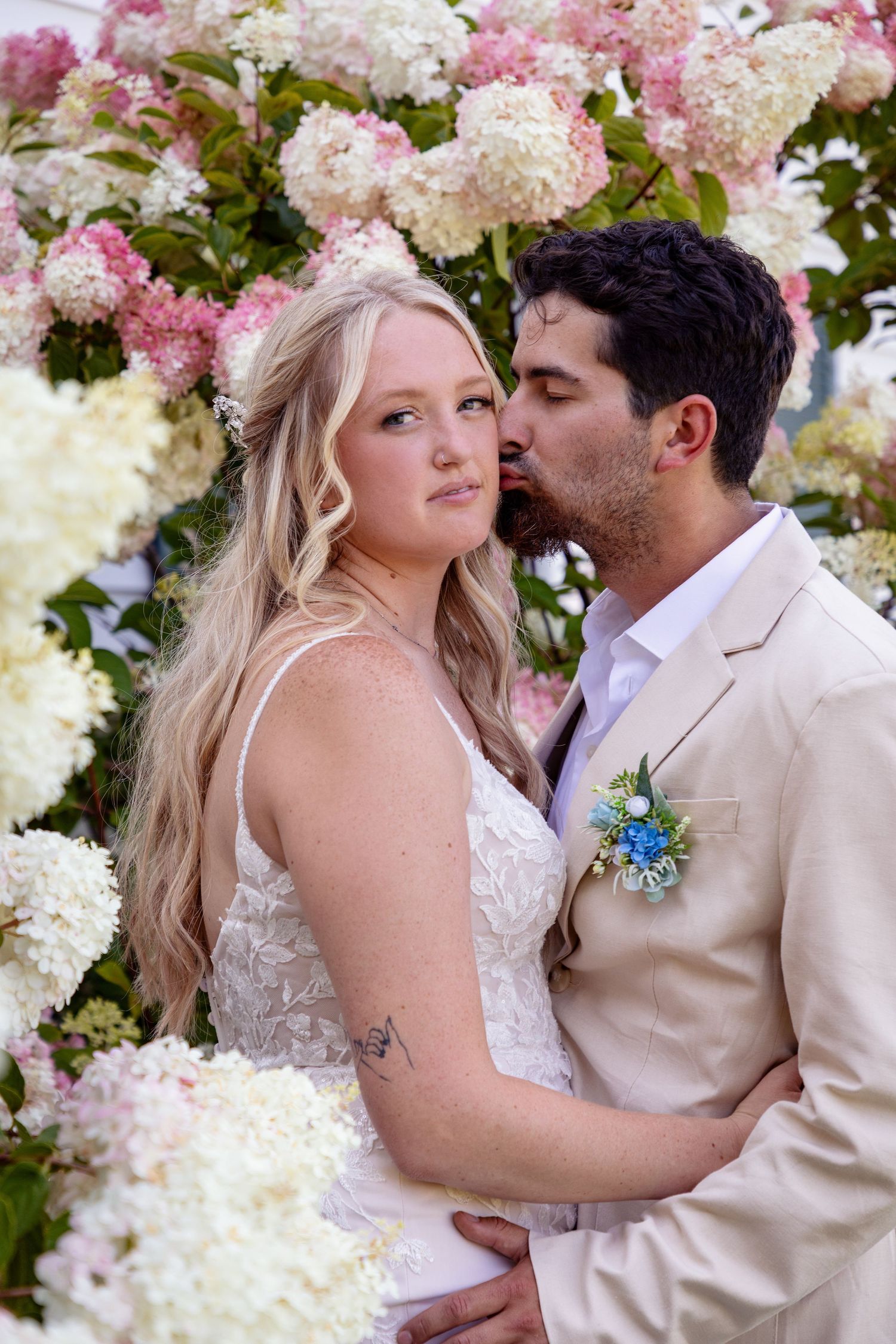 A romantic wedding portrait with pink and white hydrangea flowers creating a beautiful floral backdrop.