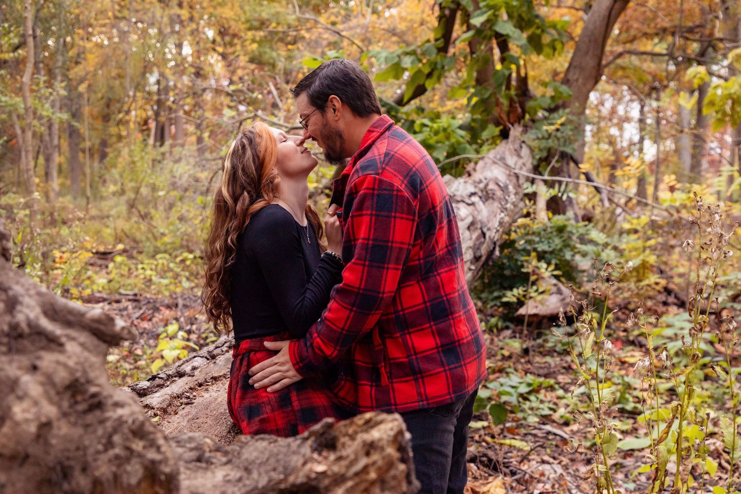 Romantic couple shares intimate moments in a wooded autumn setting.