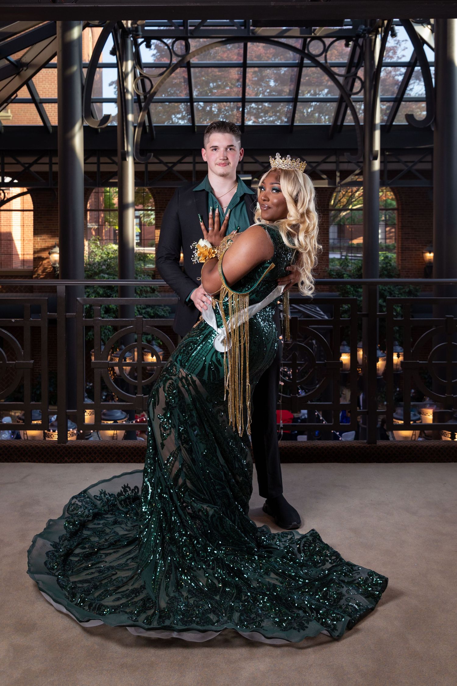 A couple in formal attire dancing and posing dramatically on a covered patio.