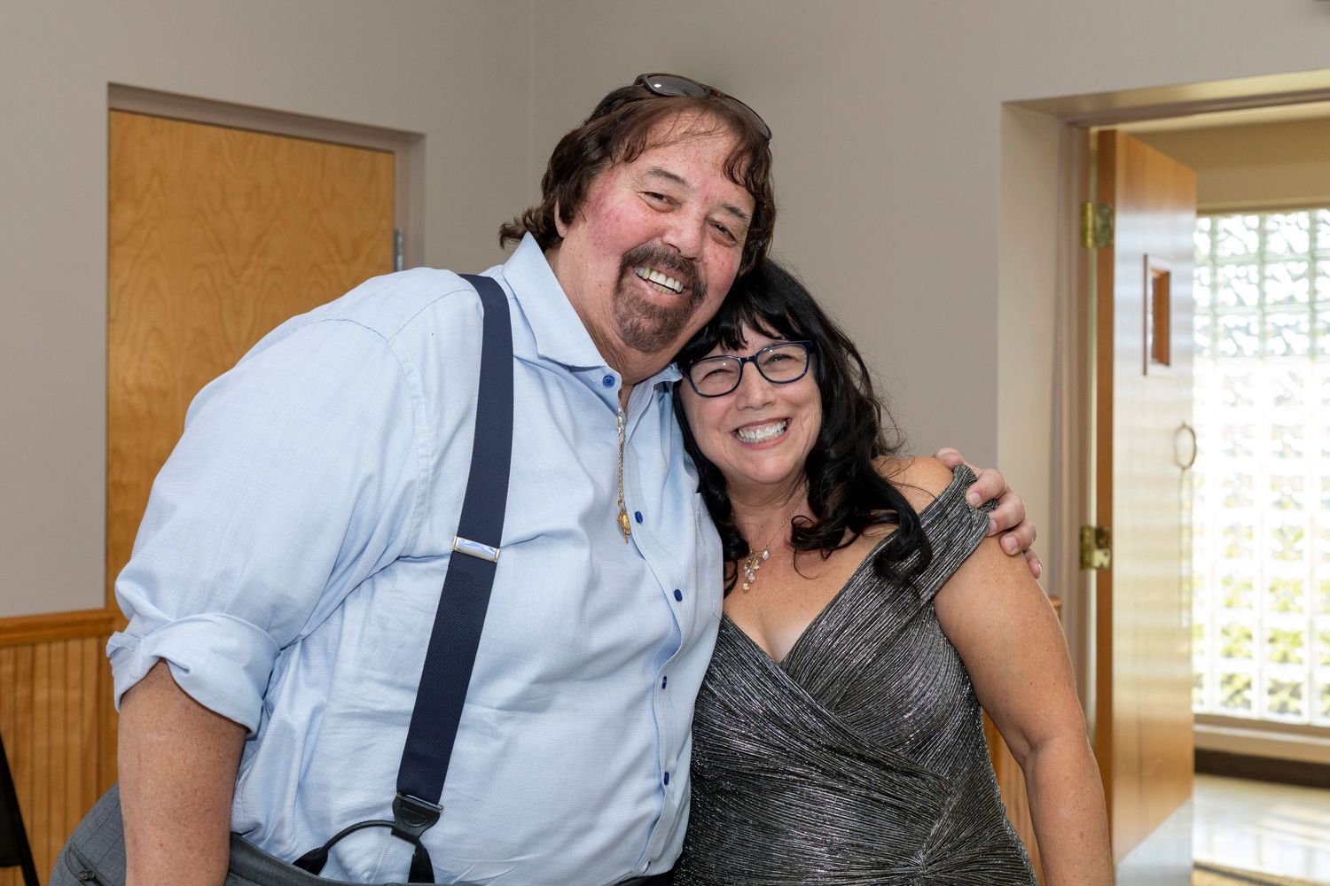 Casual friends in suspenders and casual wear sharing laughs indoors.