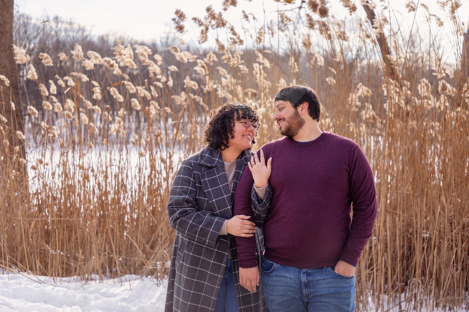Couple sharing intimate moments among golden reeds in a winter setting.