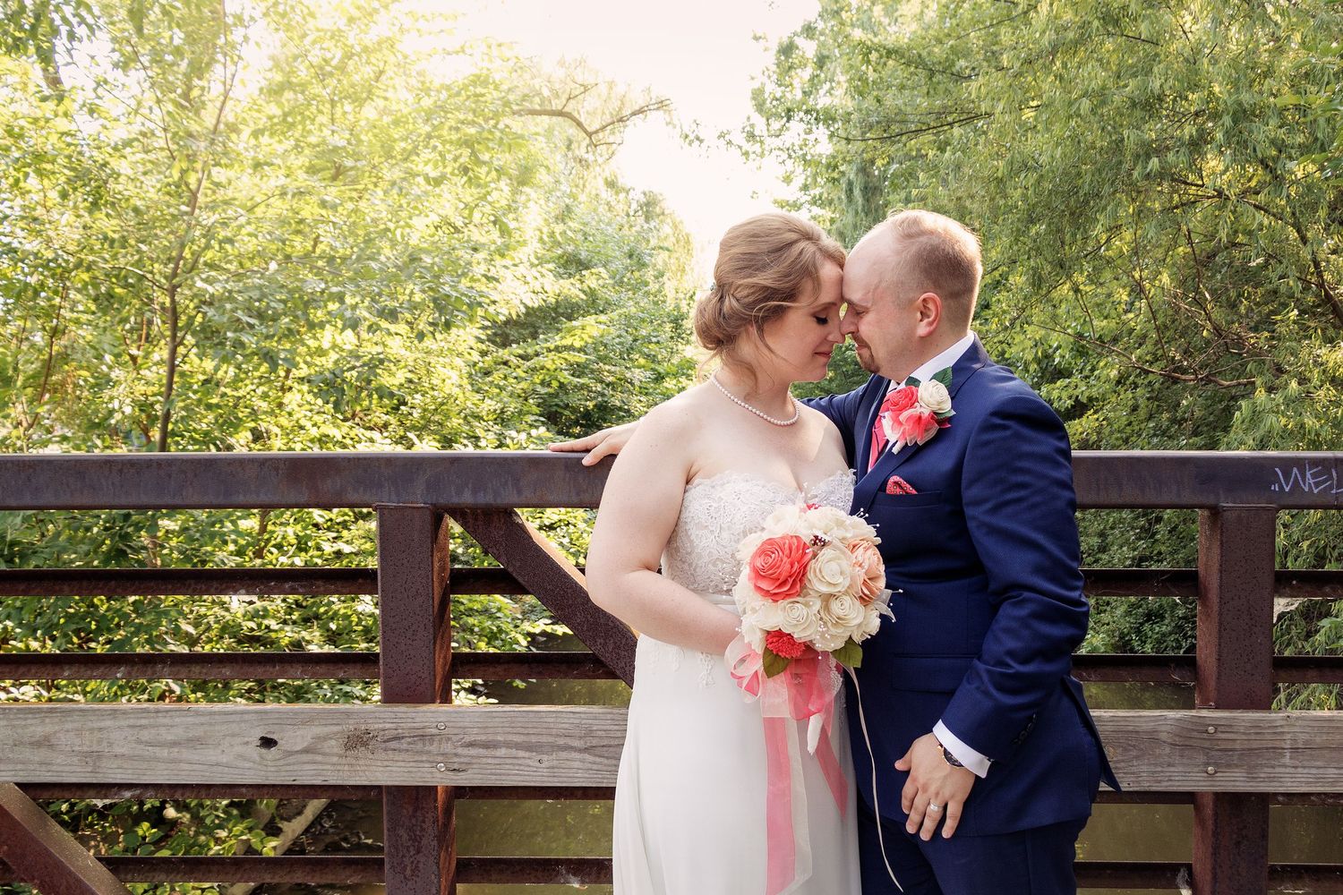 Wedding couple sharing intimate moments along a wooden railing with coral accents.