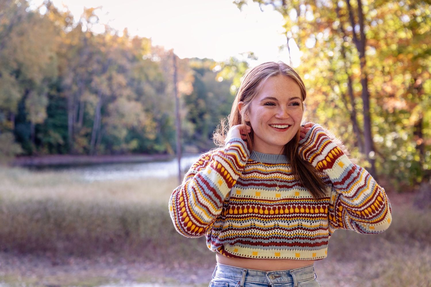 Person in striped sweater poses outdoors during autumn.