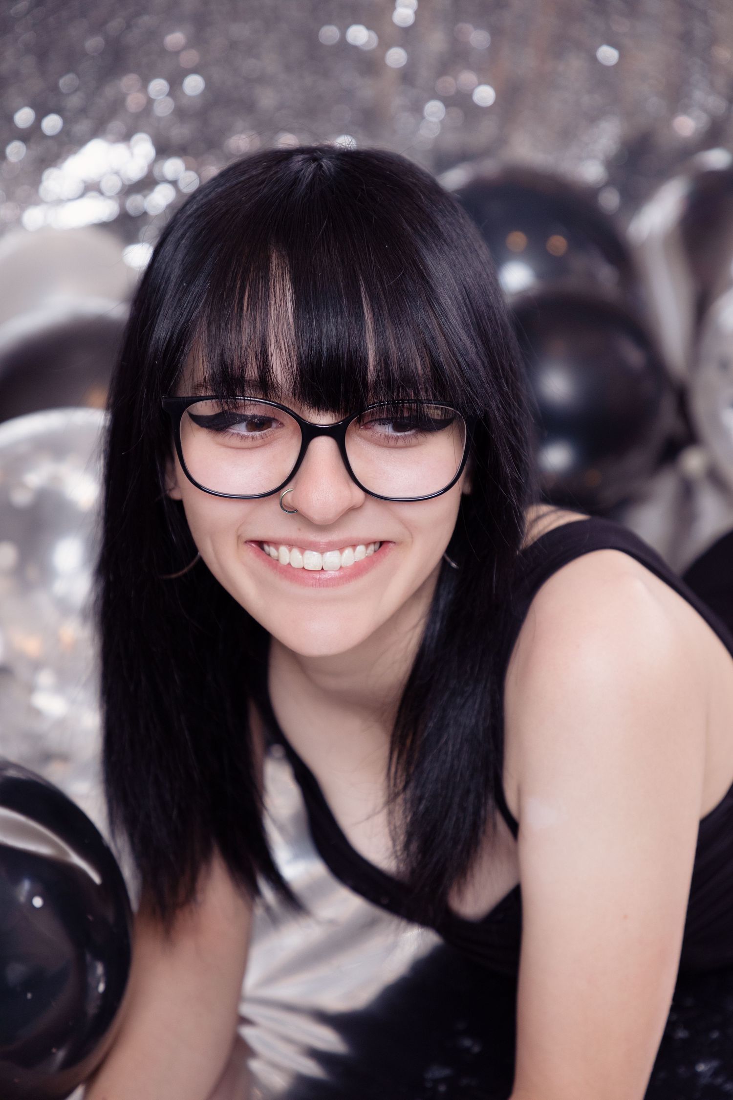 Person wearing glasses poses playfully with bokeh lights in background.