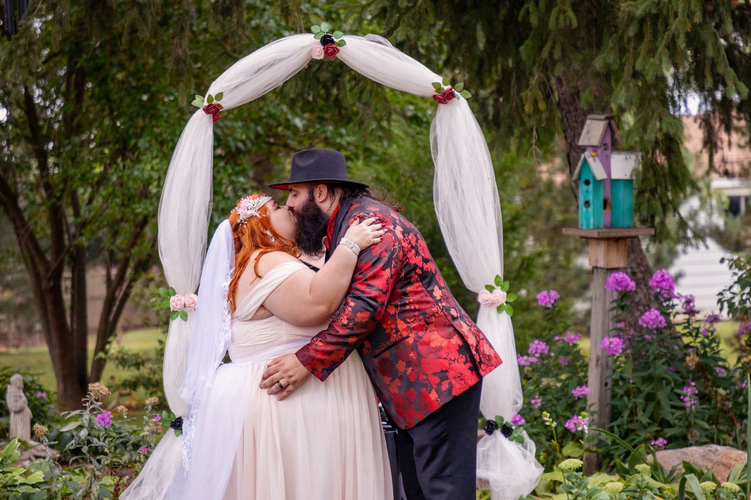 Outdoor wedding ceremony setup with white fabric arch and natural garden backdrop.
