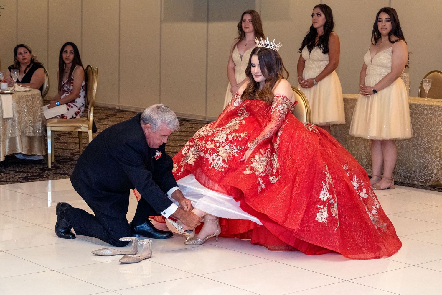 A quinceañera celebration with attendees in formal attire gathered in a reception hall.