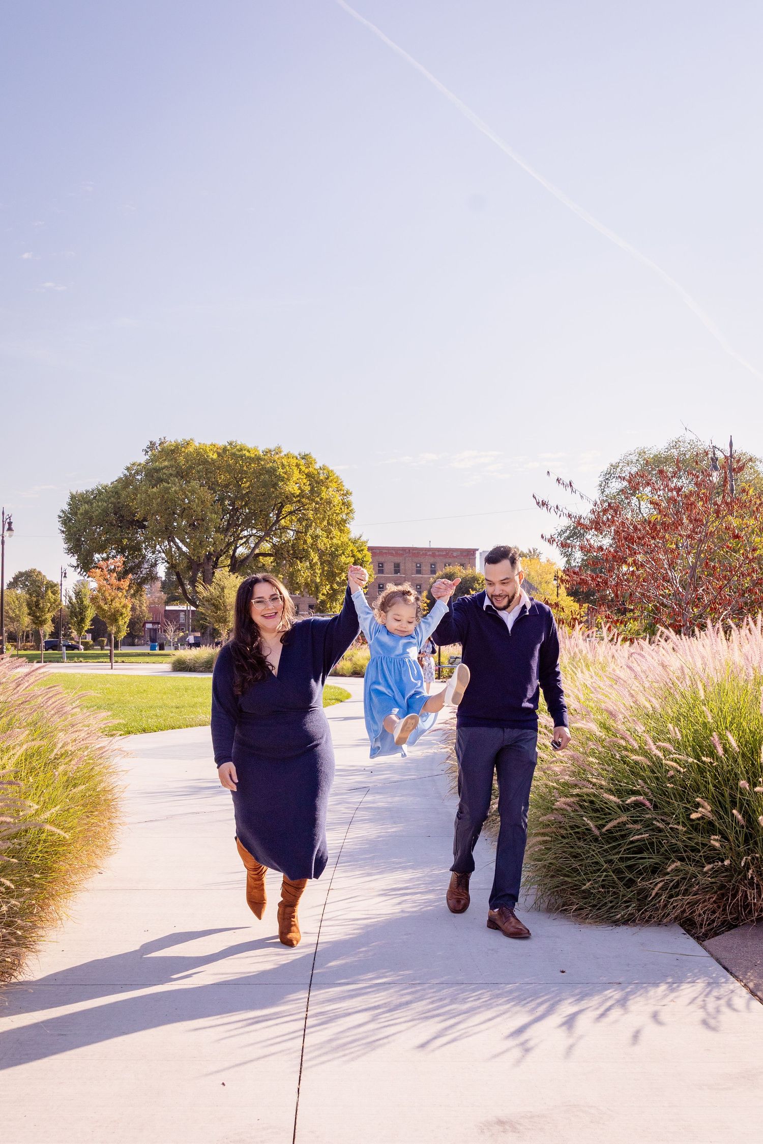 People walking together on a paved path surrounded by autumn ornamental grasses.