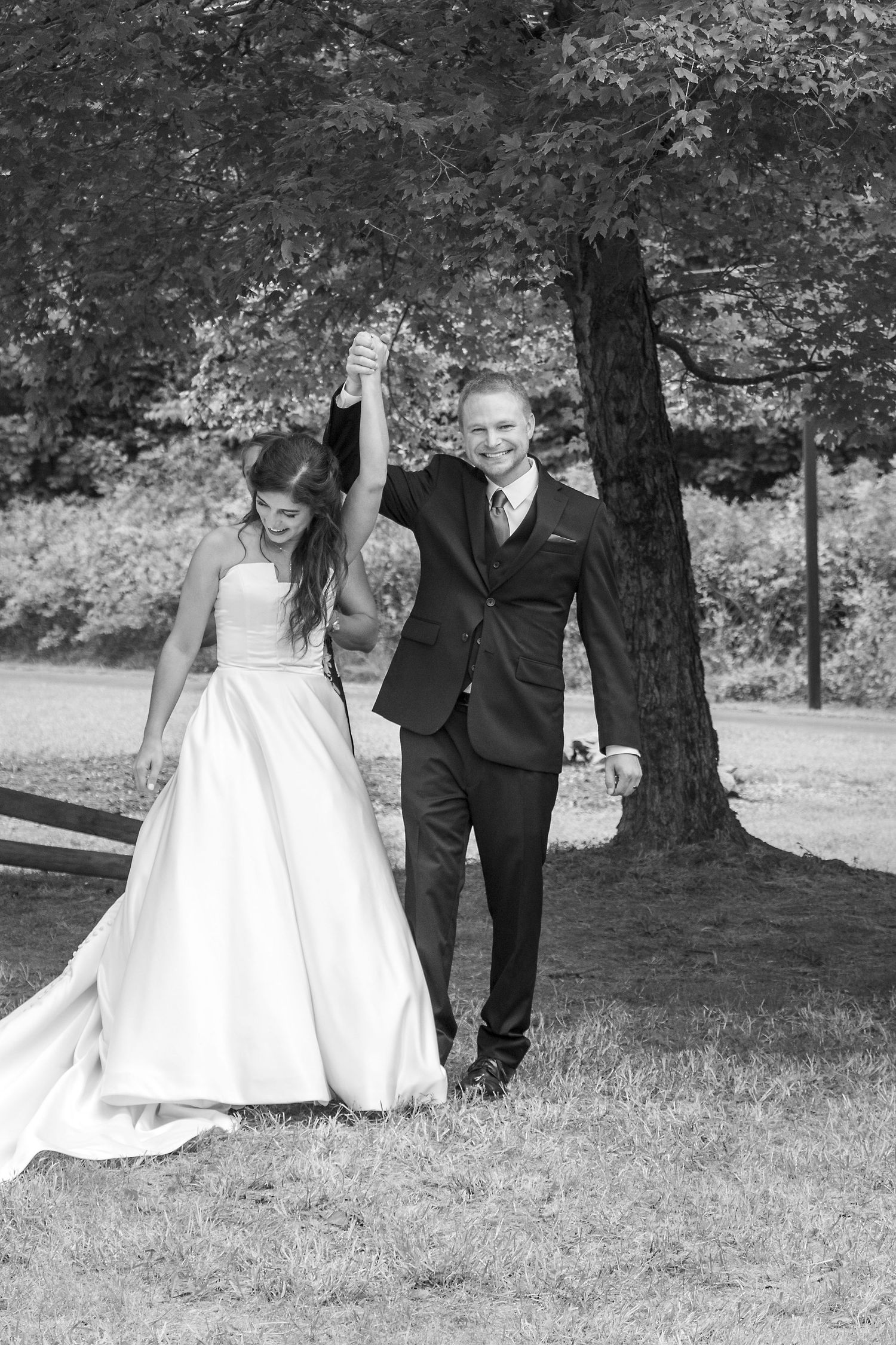 A joyful black and white photo of newlyweds celebrating outdoors.