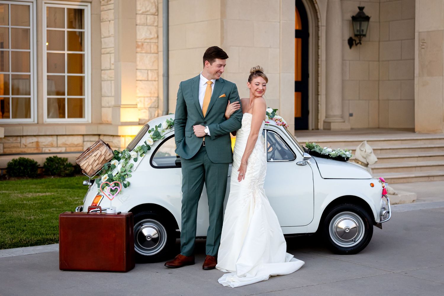 bride and groom in front of white vintage Italian fiat on the front lawn of the Olana wedding venue
