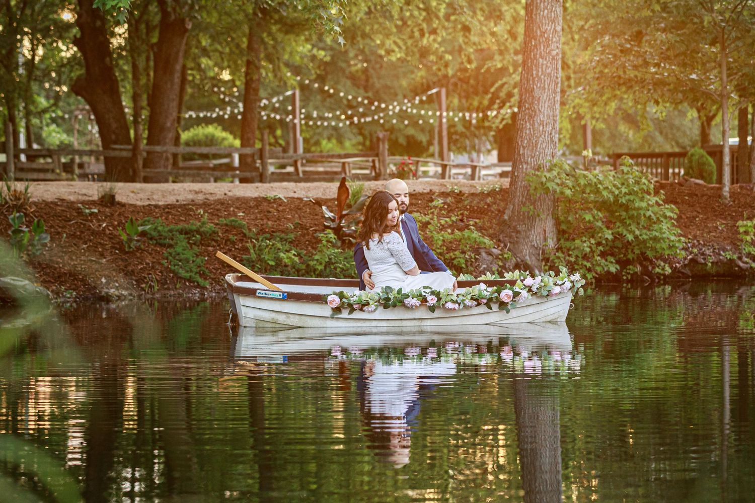 bride and groom in boat on pond at sunset