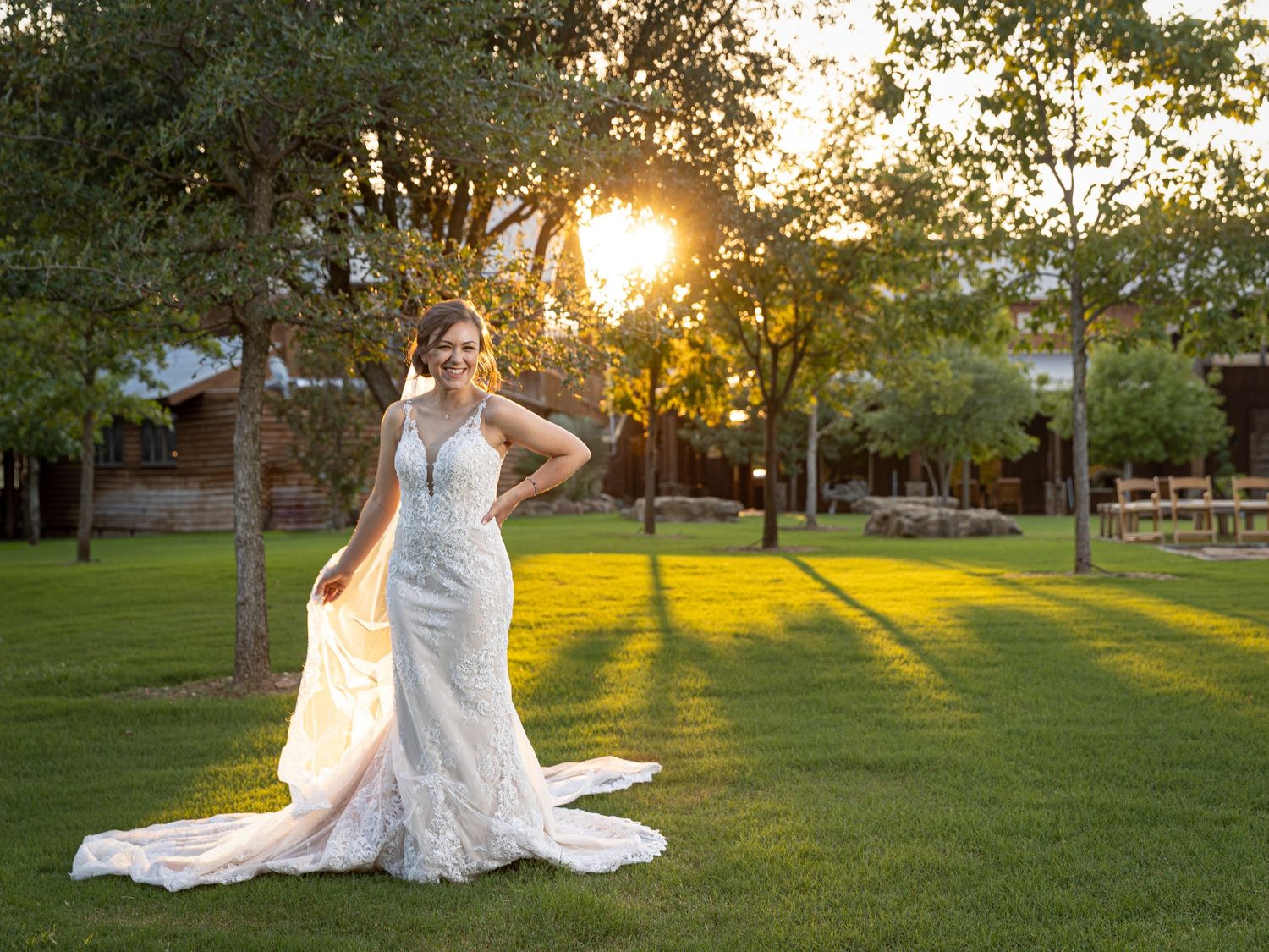 bride on the lawn of wooded venue at sunset