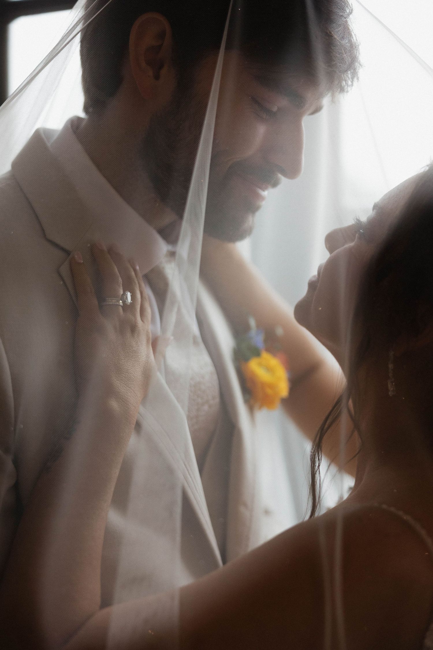 Soft focus artistic wedding photography showing intimate moments through sheer fabric.