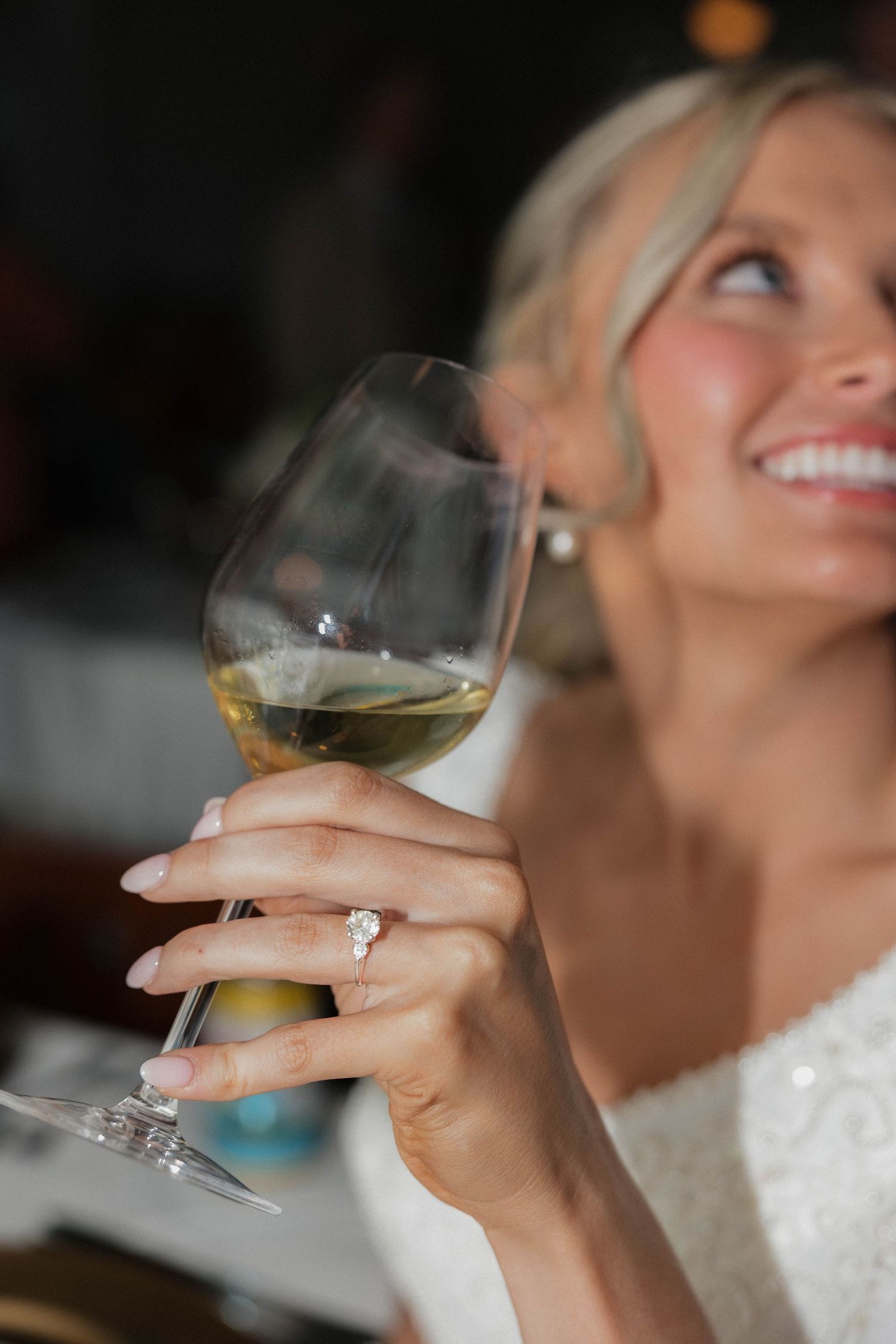 Wedding guests raise wine glasses in celebration during a reception toast.