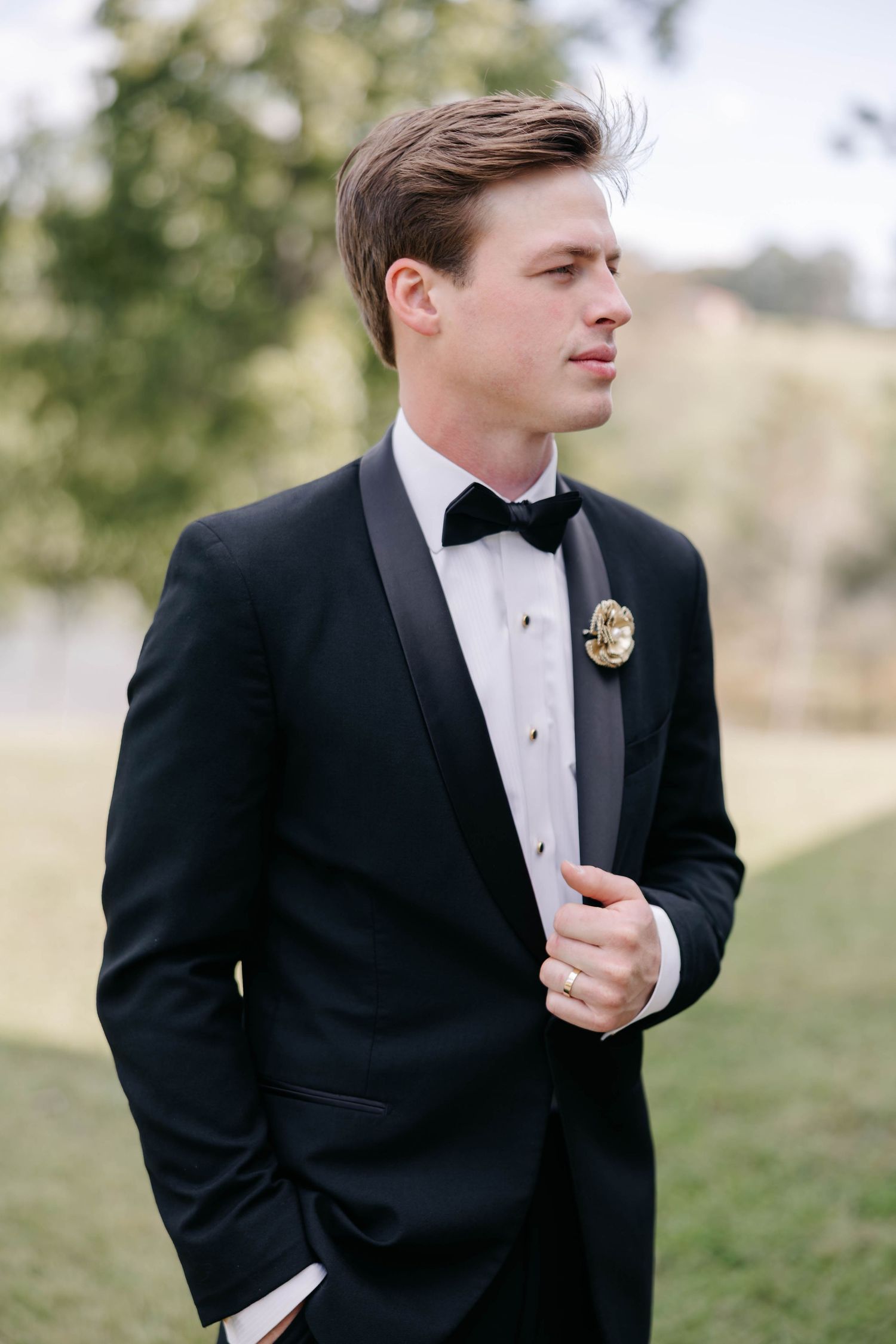 A groom in a classic black tuxedo and bowtie poses outdoors in a series of candid shots.