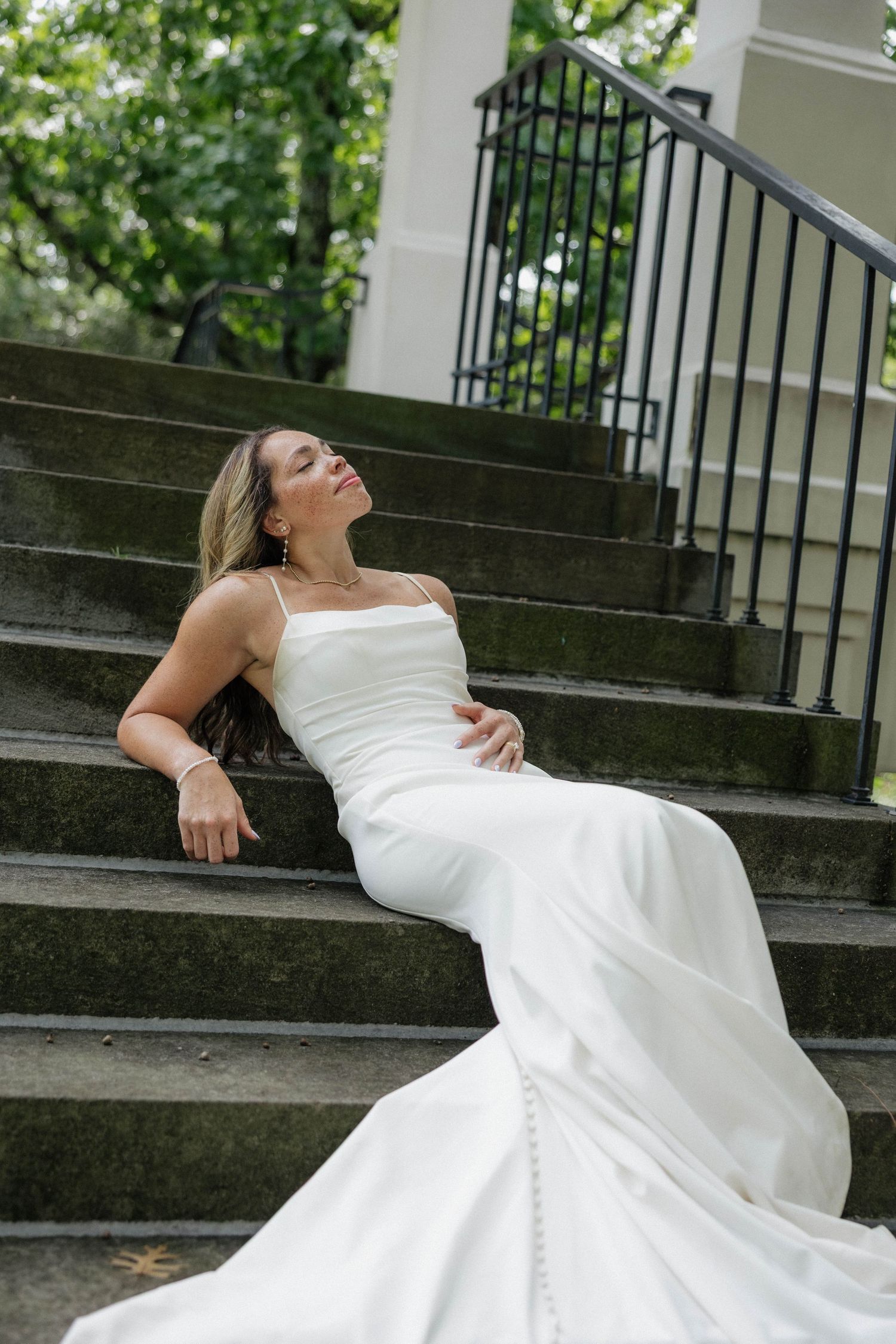 Wedding dress photoshoot on stone steps with dramatic pose and flowing white fabric.