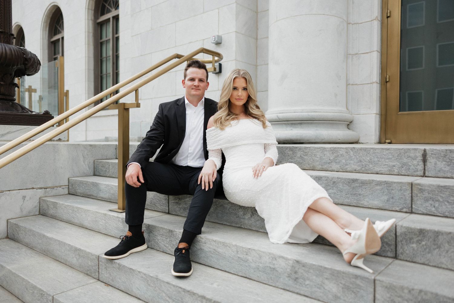 Elegant wedding couple takes creative photos on marble steps of a historic building.