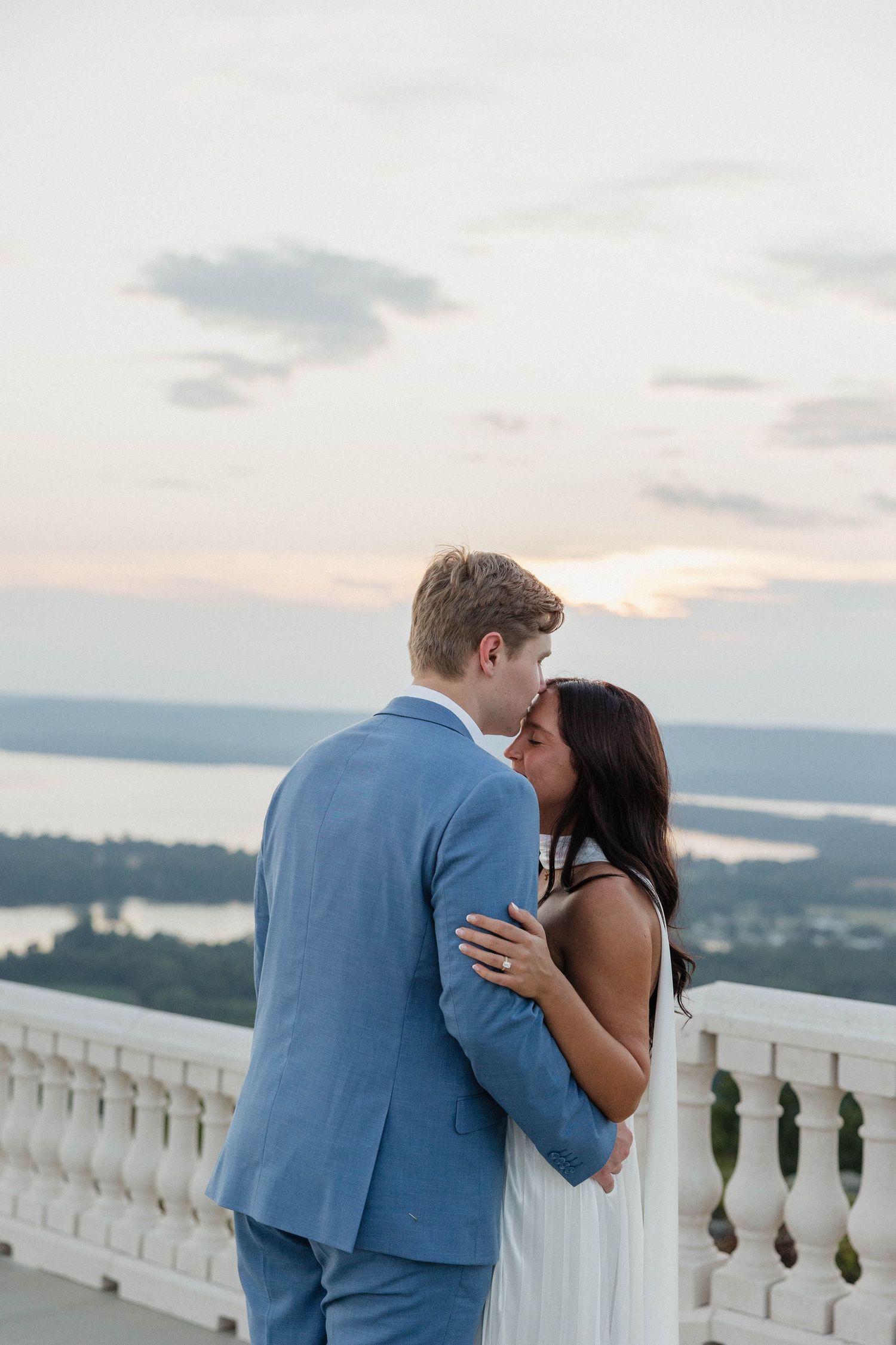 Intimate moment between newlyweds on a terrace with a stunning mountain landscape in the background.