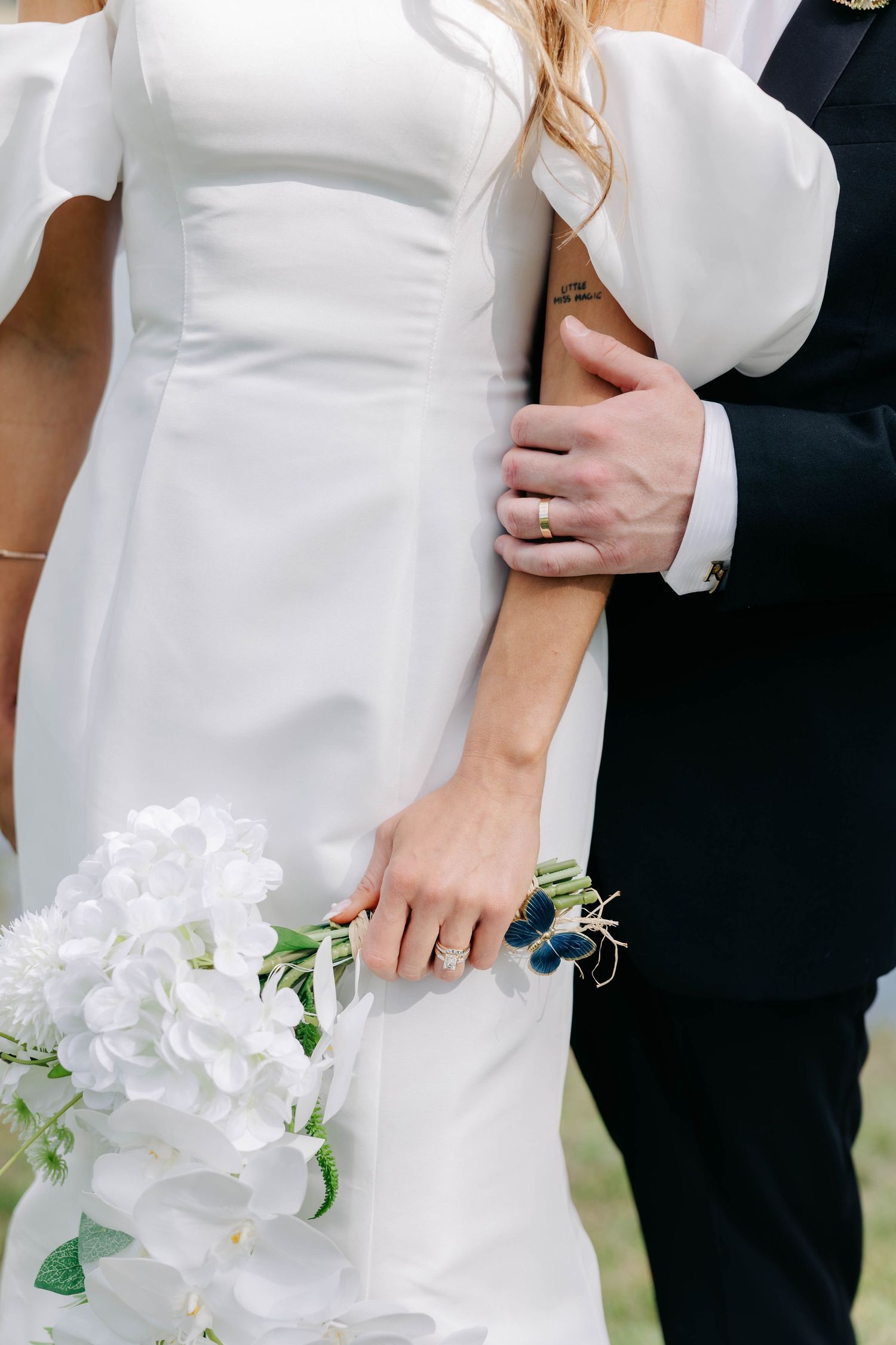 Close-up details of a bride's white wedding dress and bouquet featuring white orchids.