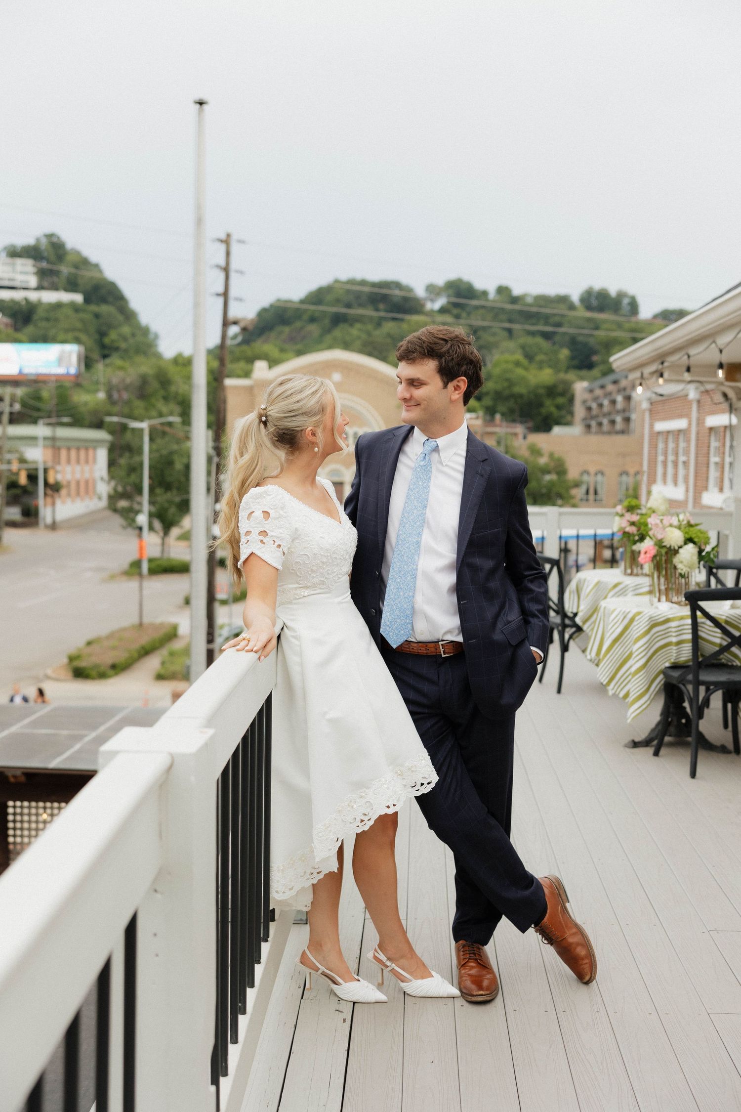 A couple shares a romantic moment on a wooden deck overlooking a small town.