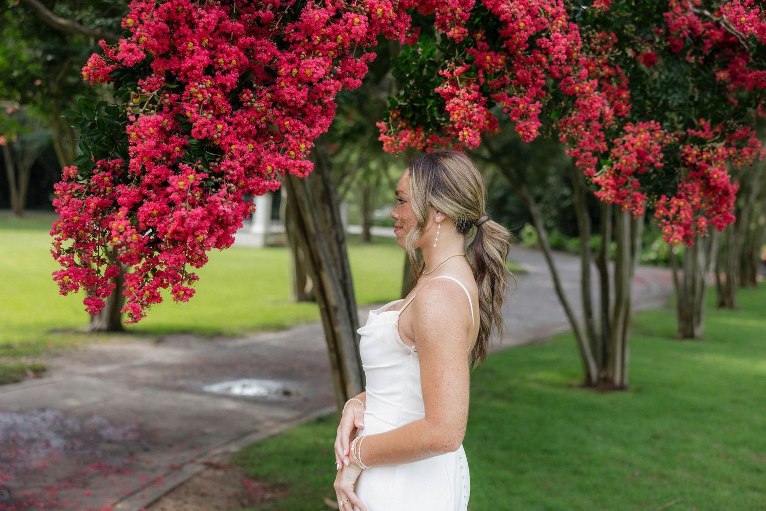 Wedding dress portrait with vibrant red flowering trees in background.