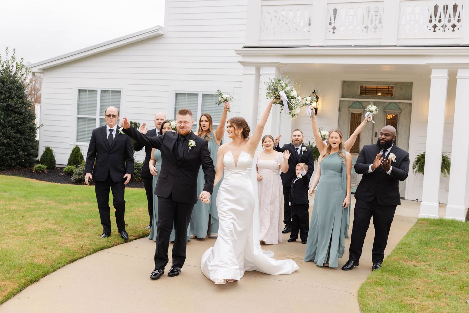 Wedding guests gather outside white house for group photos.