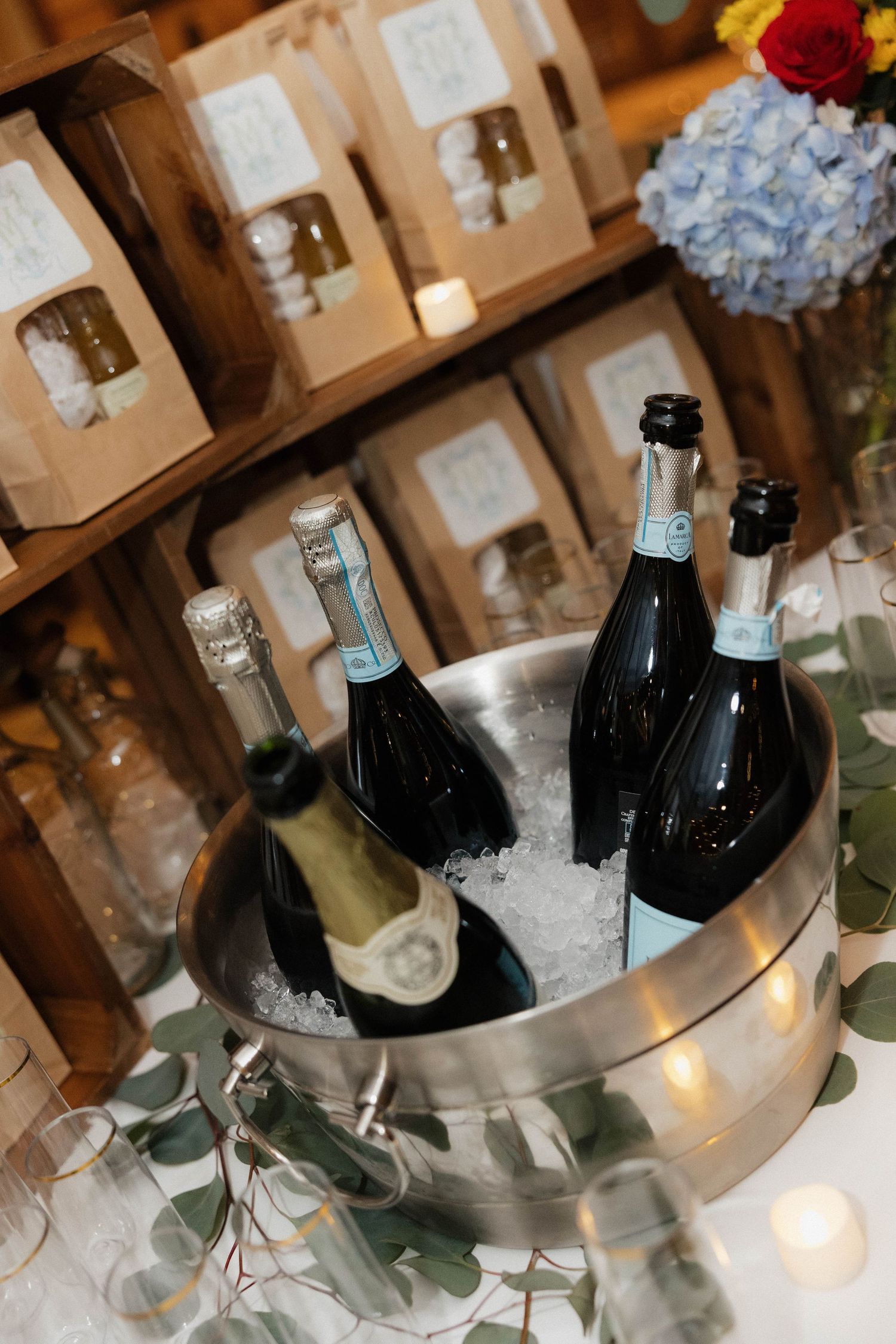 Champagne bottles chilling in ice bucket with eucalyptus garnish at wedding reception.