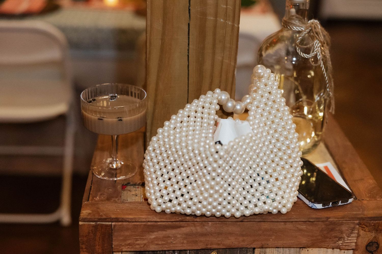 Pearl-encrusted wedding accessories displayed on rustic wooden surface with warm lighting.