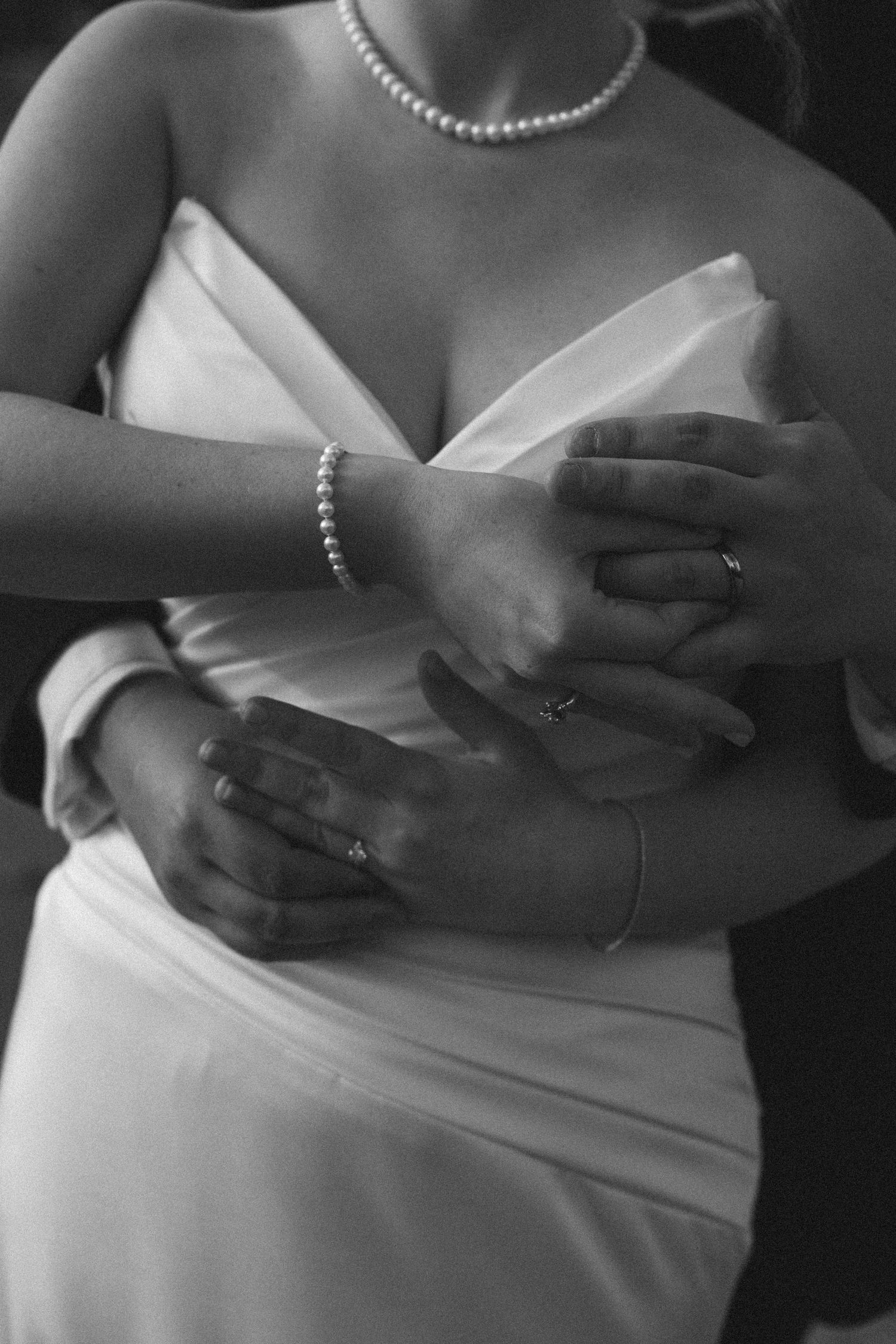 Close-up of pearl necklace and white wedding dress bodice details.