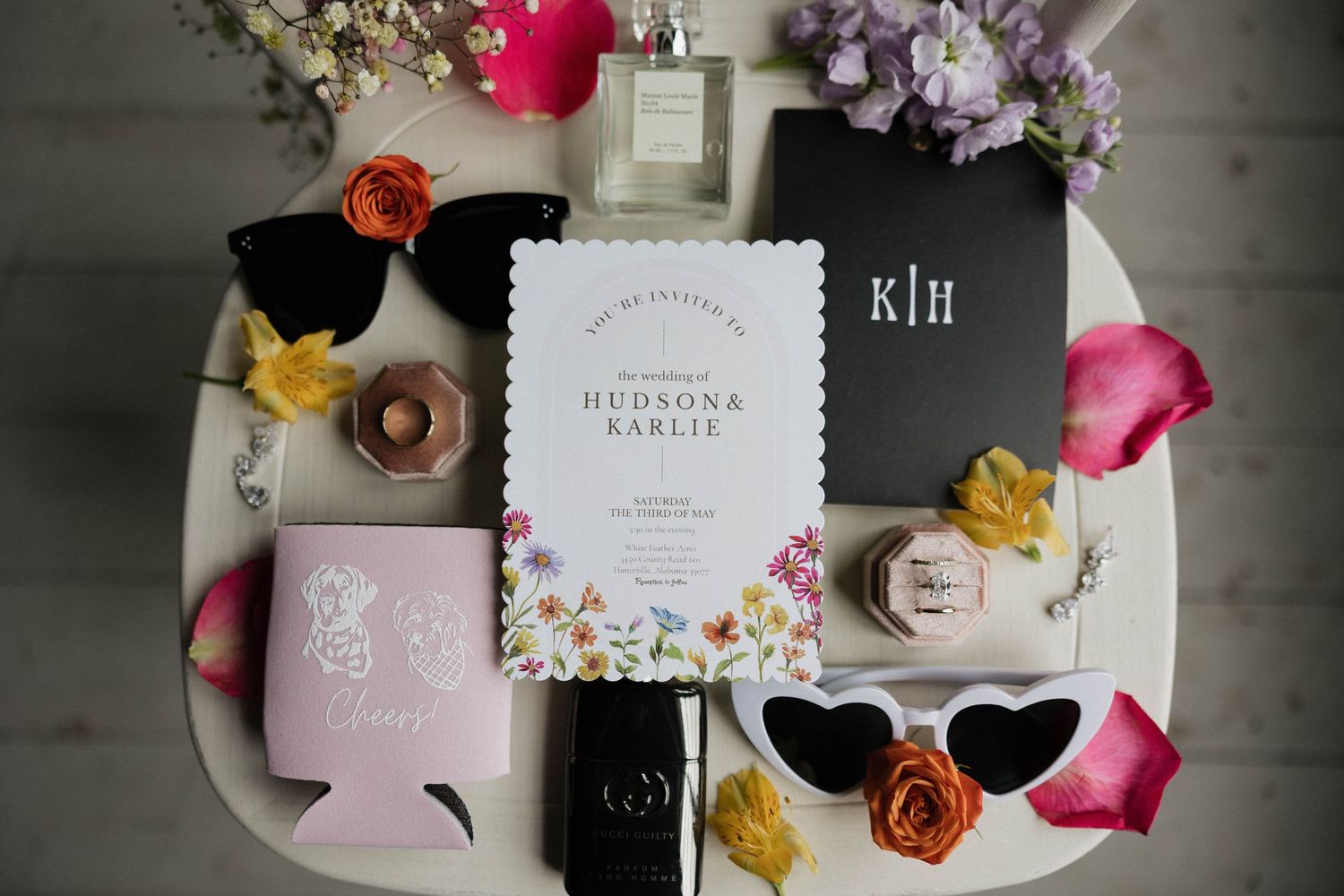 Wedding invitations and stationery laid out with flower petals and decorative elements.