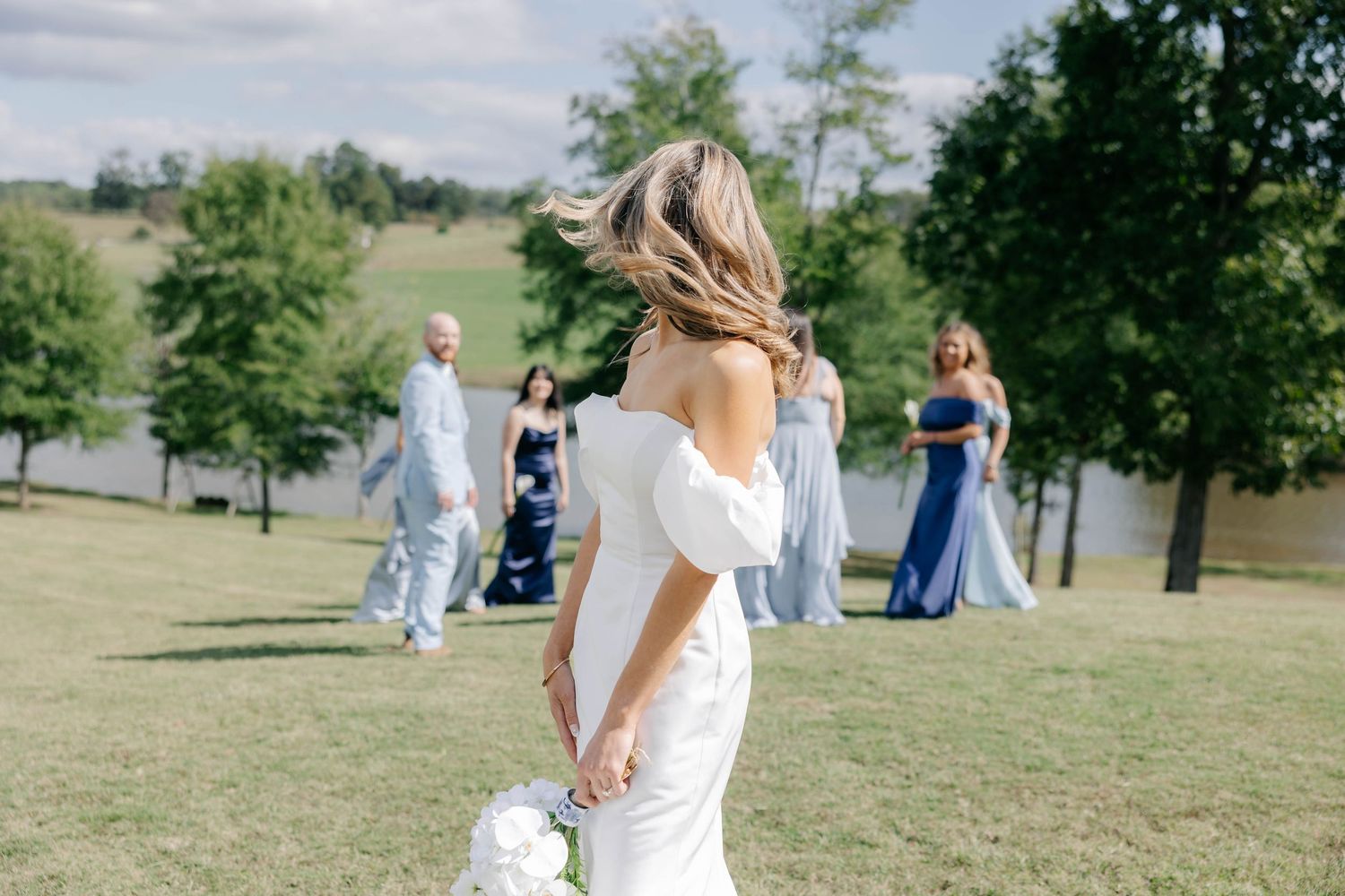 Bride walking along outdoor pathway in flowing white wedding gown.