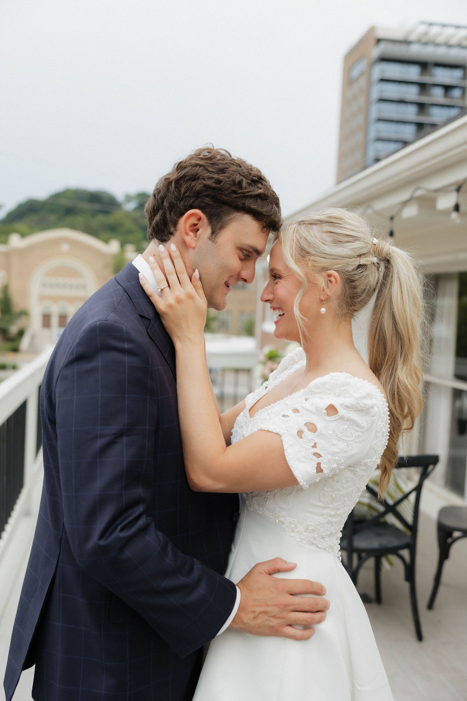 Romantic couple in wedding attire share intimate moments on a balcony.