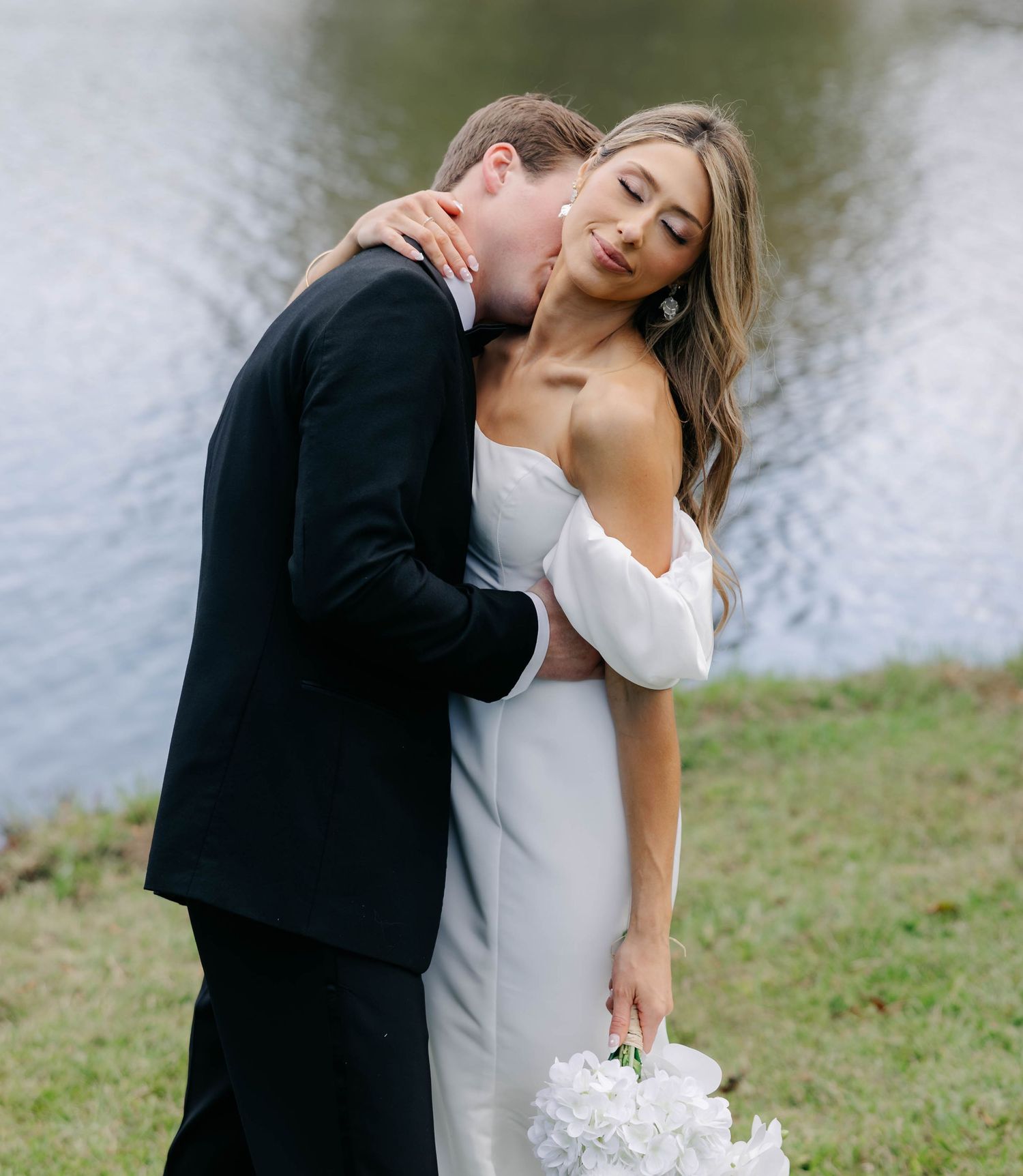 Romantic waterfront wedding portrait with couple in formal attire.