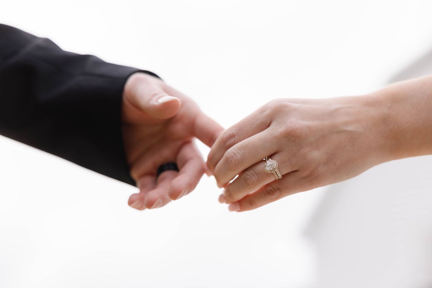 Close-up shot of two hands with wedding rings touching in a gentle gesture.