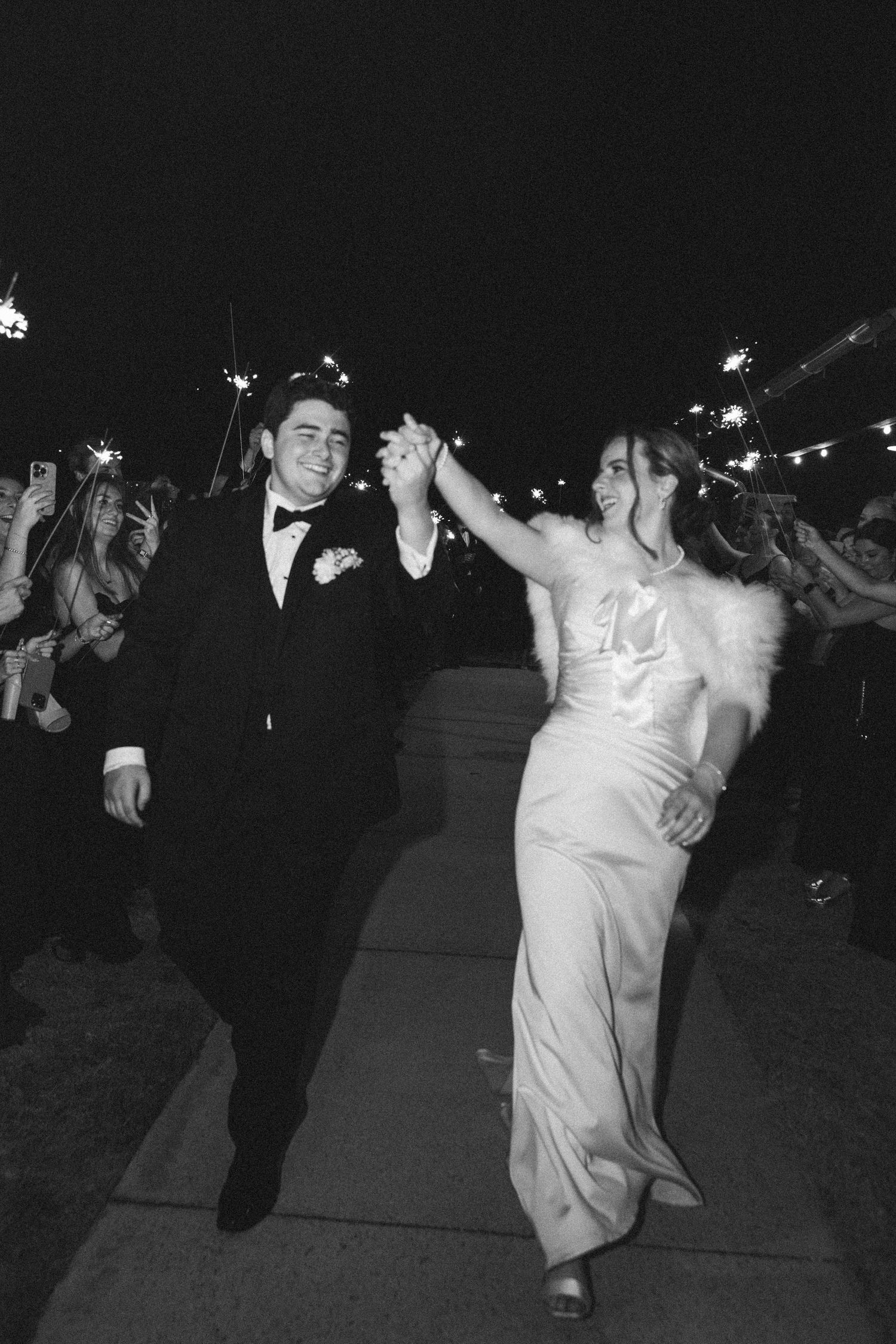 Wedding reception guests dancing outdoors at night under string lights.