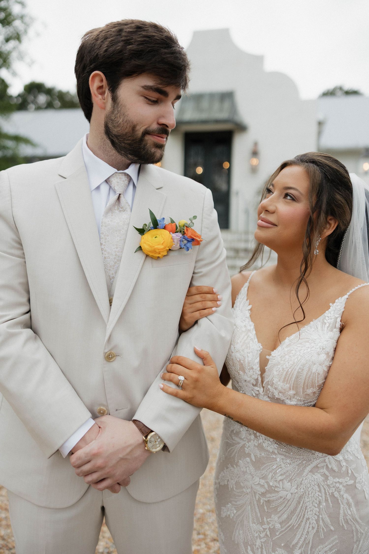 Wedding couple in cream suit and lace dress share playful moments during photo session.