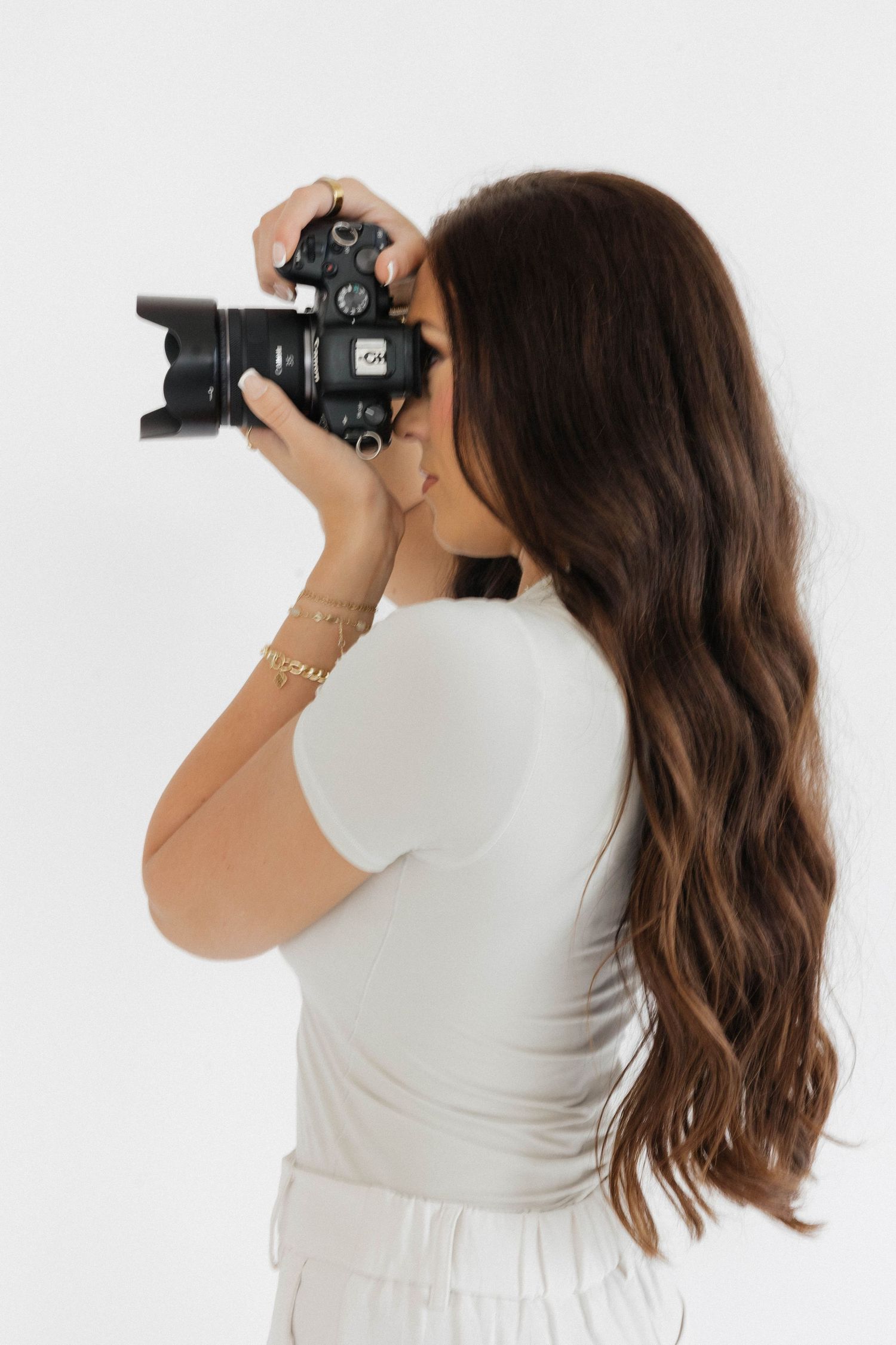 Side view of photographer using professional camera against white background.