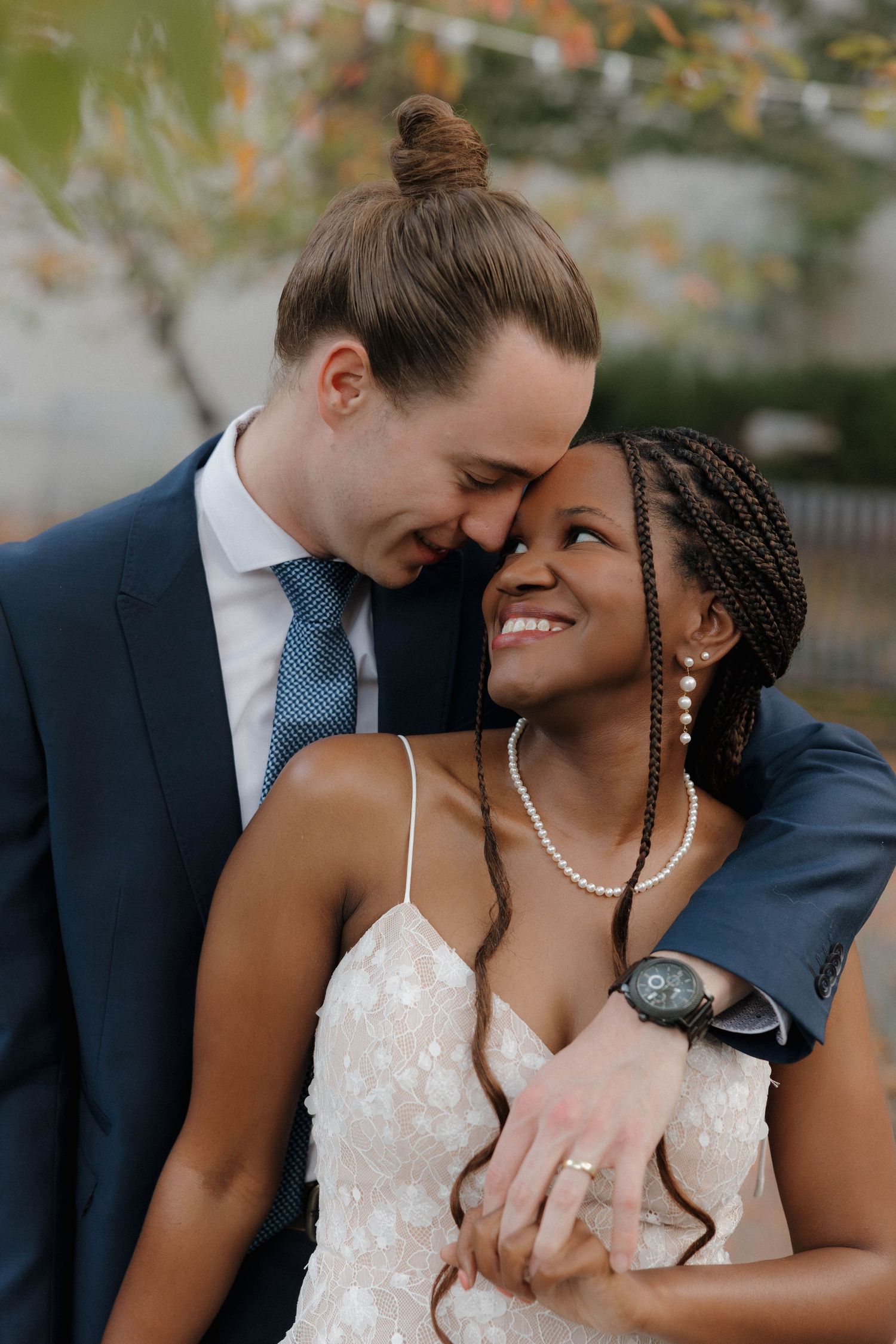 A joyful outdoor portrait of a couple in wedding attire sharing an intimate moment.