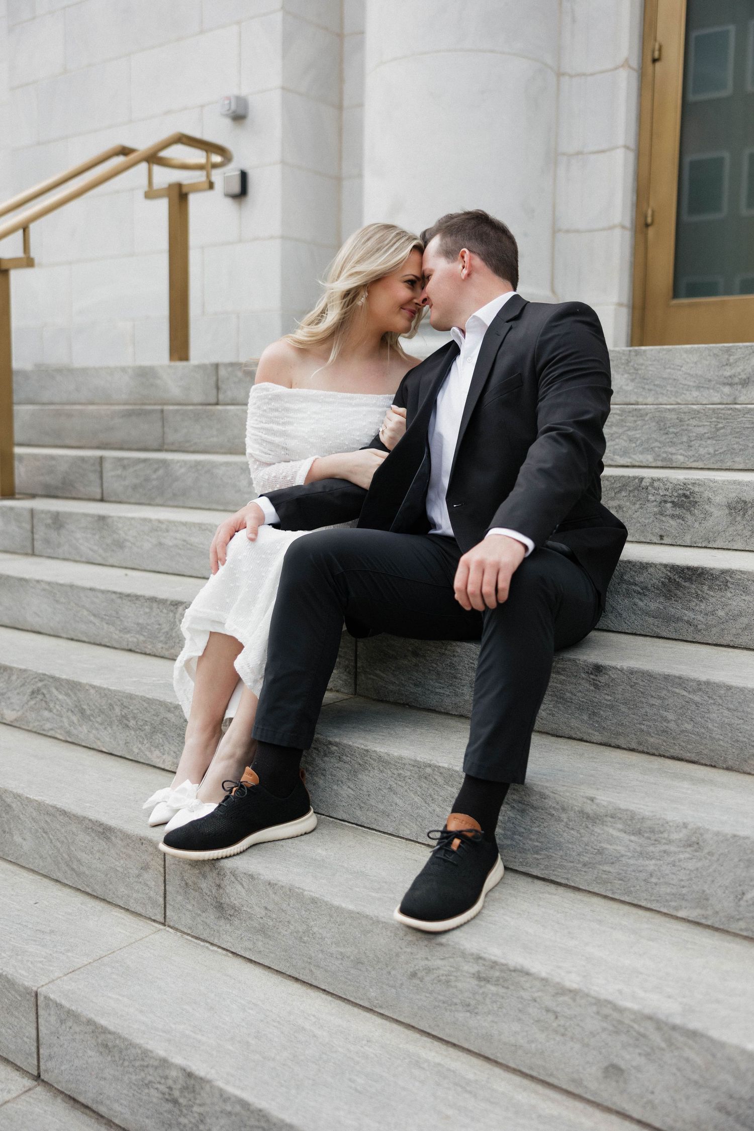 Couple in formal wear shares intimate moments while sitting on marble steps.
