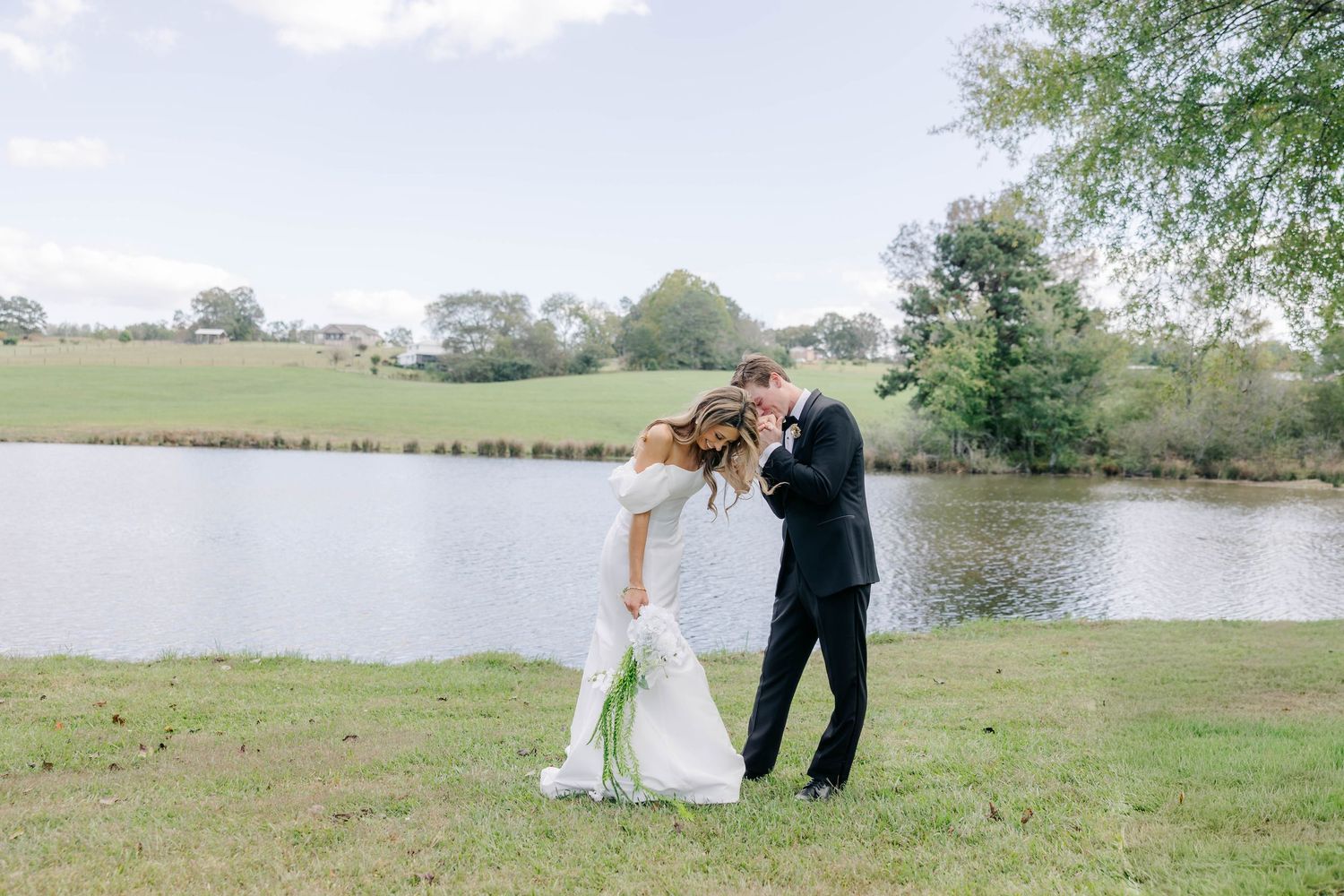 Wedding couple poses for romantic photos in a scenic outdoor setting by a lake.