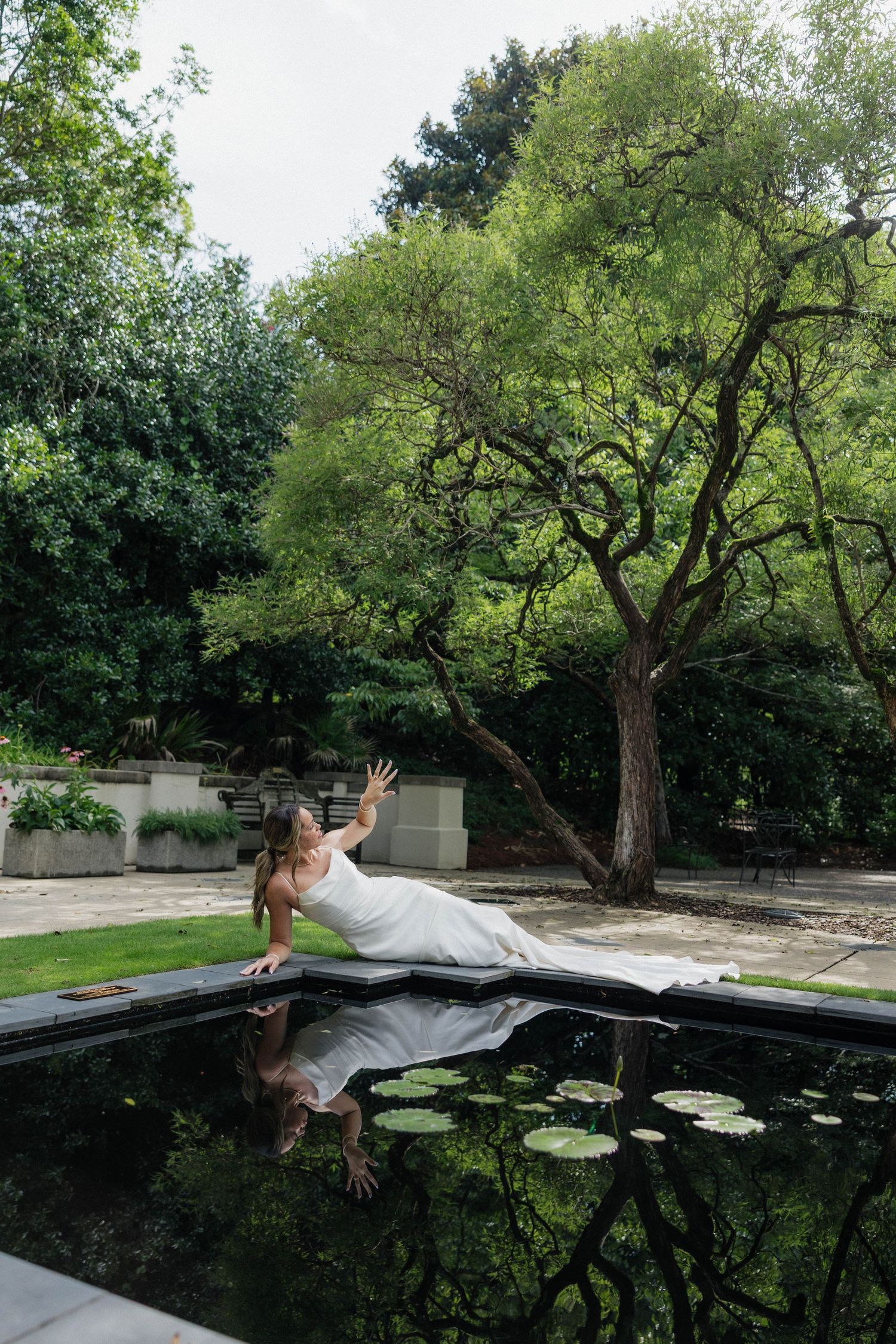Sequence showing person interacting with reflection in garden pond with lily pads.