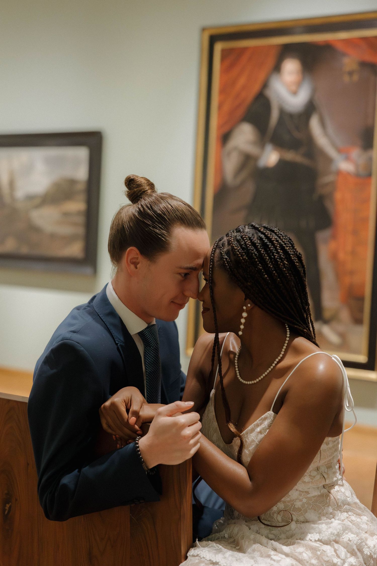 A romantic moment between a couple in formal attire sharing an intimate moment in an art gallery.